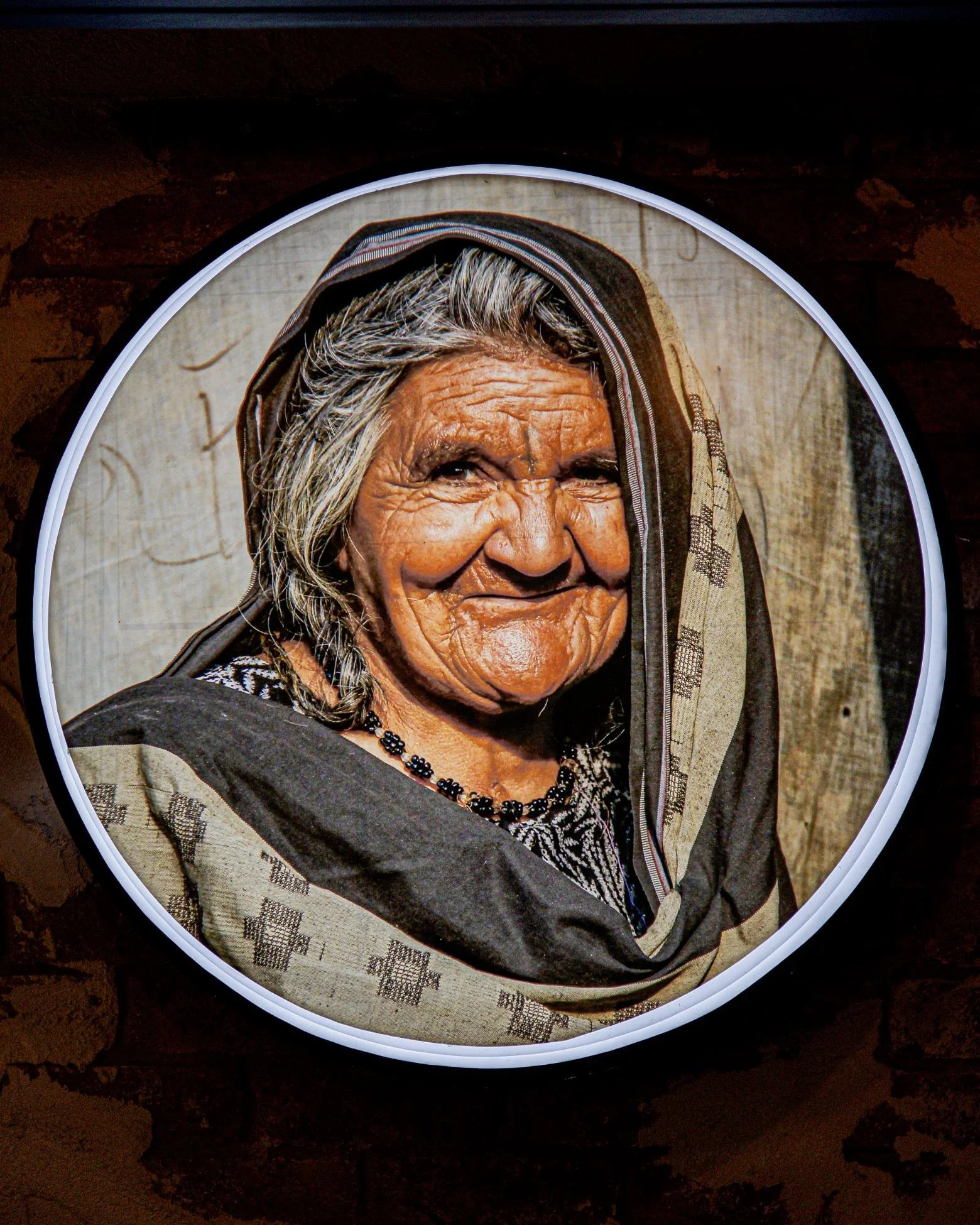 Photograph of an elderly woman with gray hair, wearing traditional clothing and jewelry, smiling.
