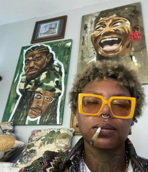 Collector in yellow glasses in front of her portraits