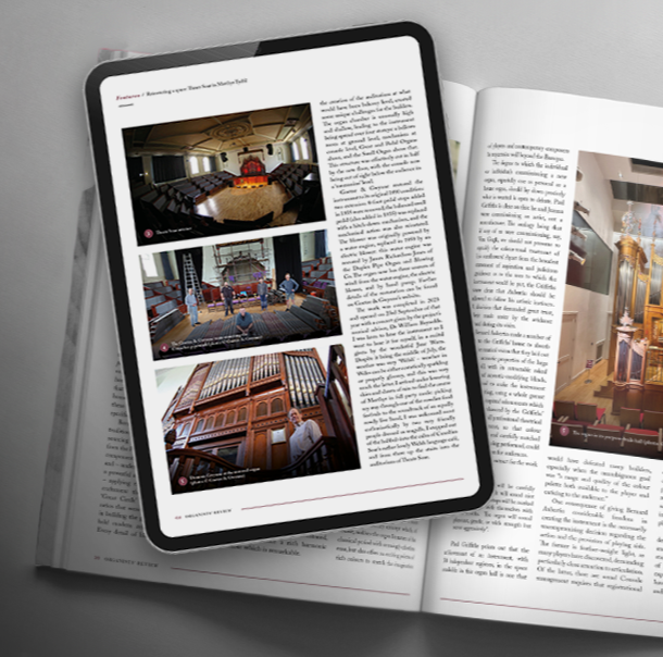 A tablet displaying images of a concert hall or theater, with photos of stage setups and interior architecture, resting on an open magazine with similar interior images.
