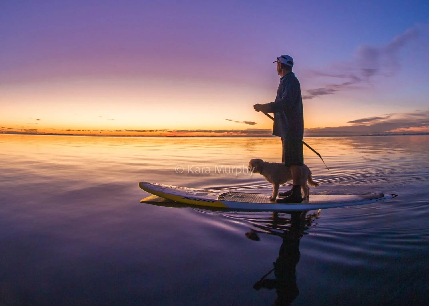Best friends paddle together, as the sun rises over Moreton Bay,