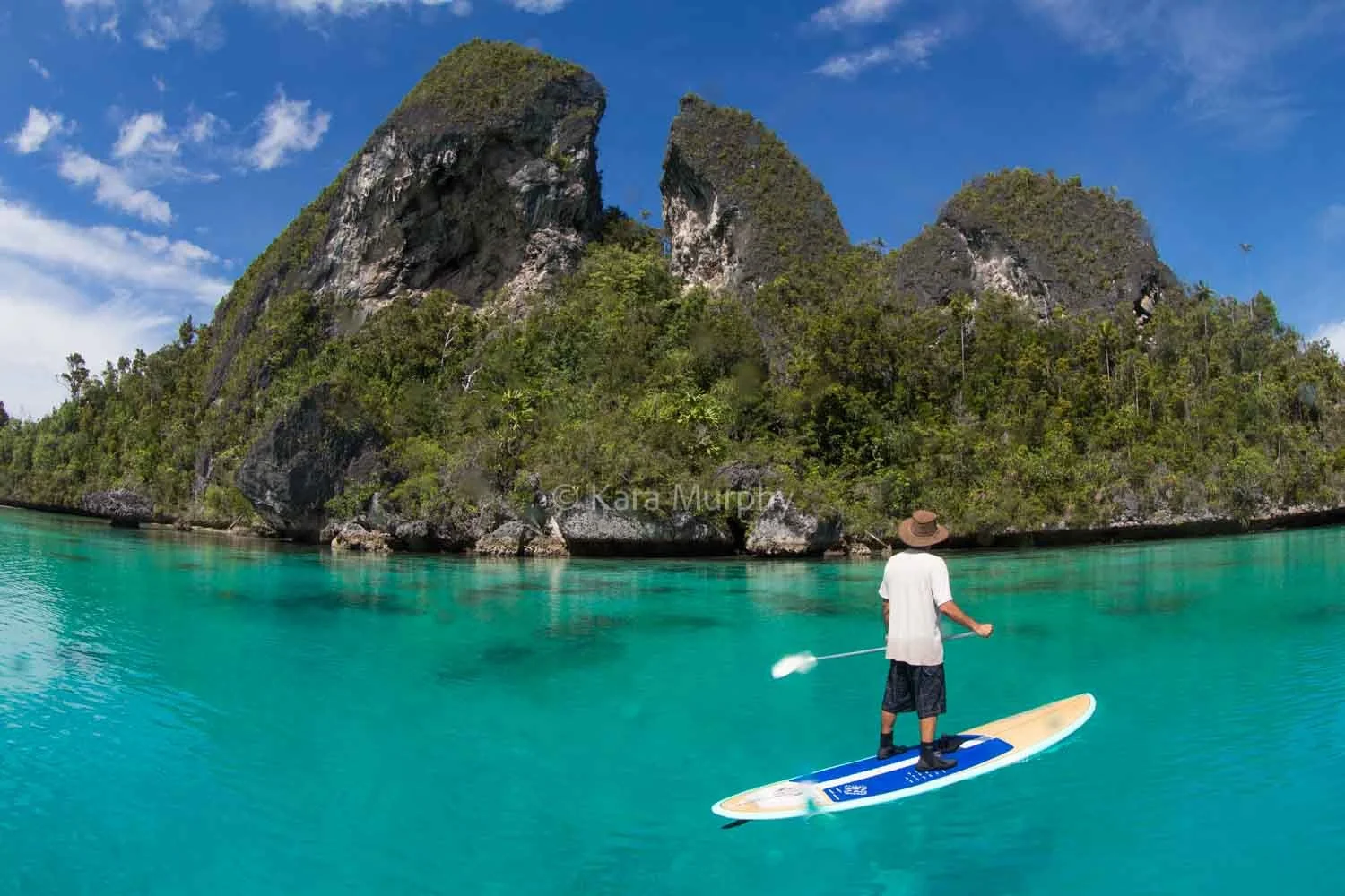 Paddleboarding against the backdrop of Wayag Island's spectacular karst scenery, Raja Ampat.