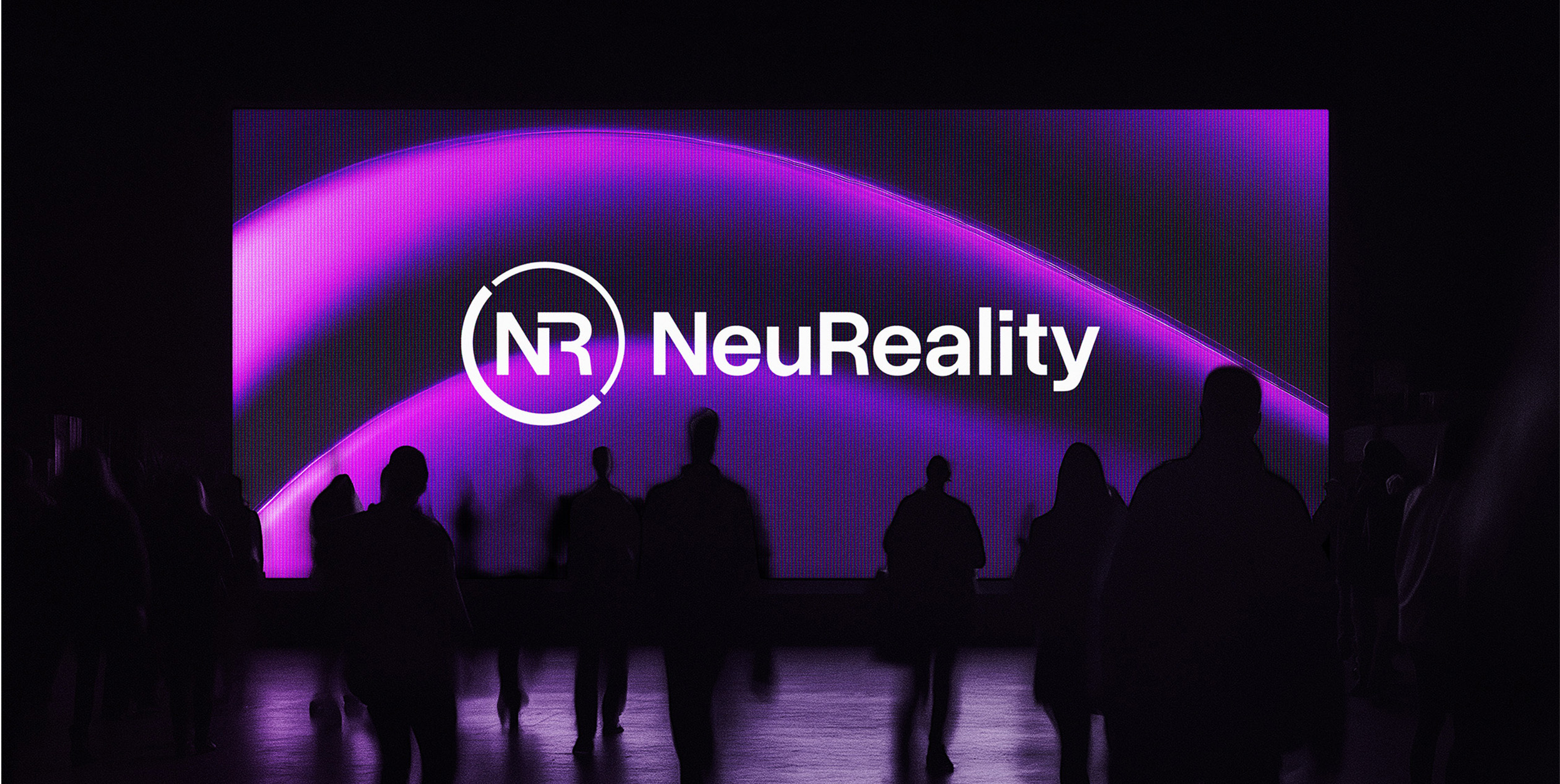 Silhouettes of people at a technology event watching a large screen displaying the NeuReality logo with purple and pink abstract background.