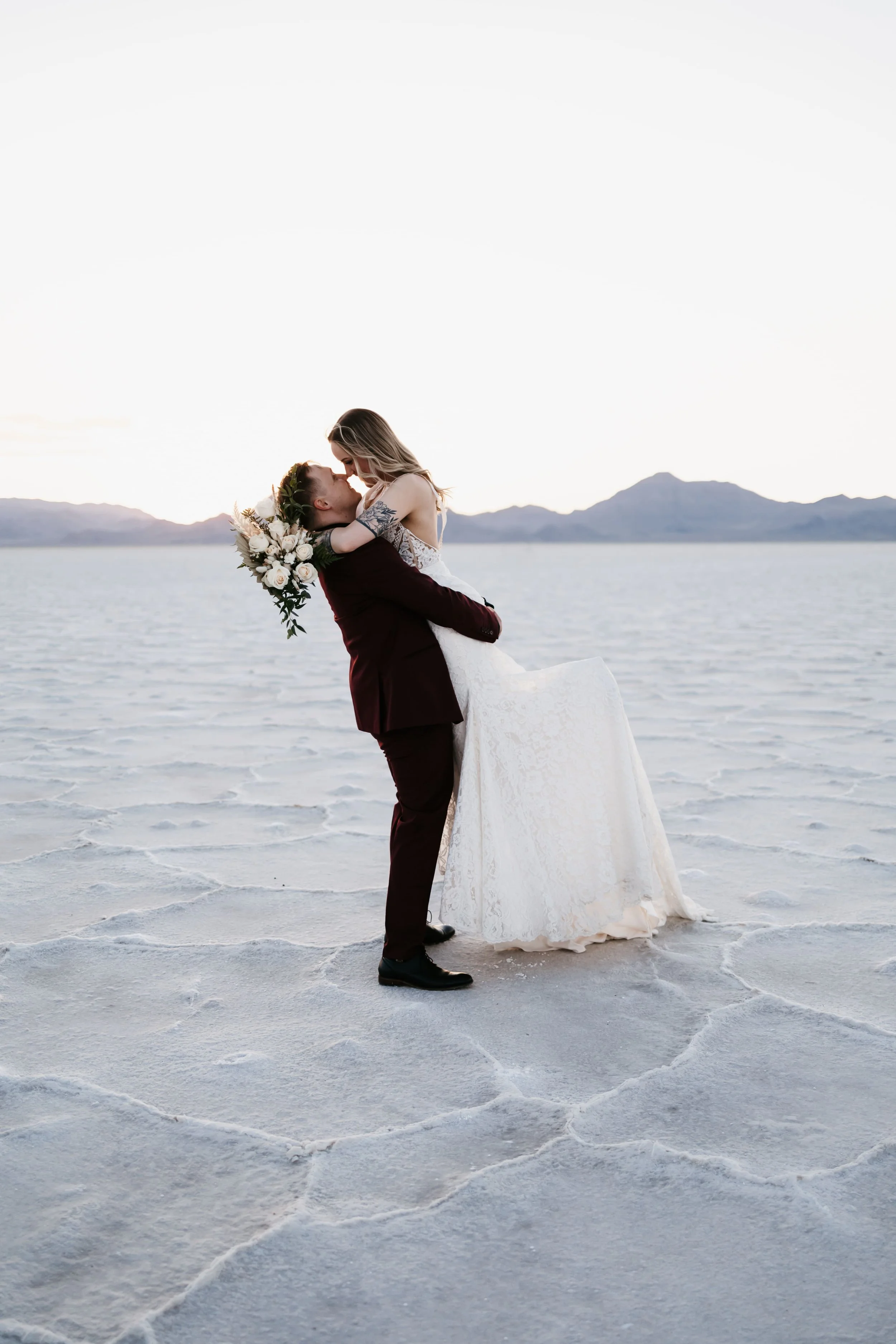 Utah bride and groom at the Salt Flats, holding a white bouquet.