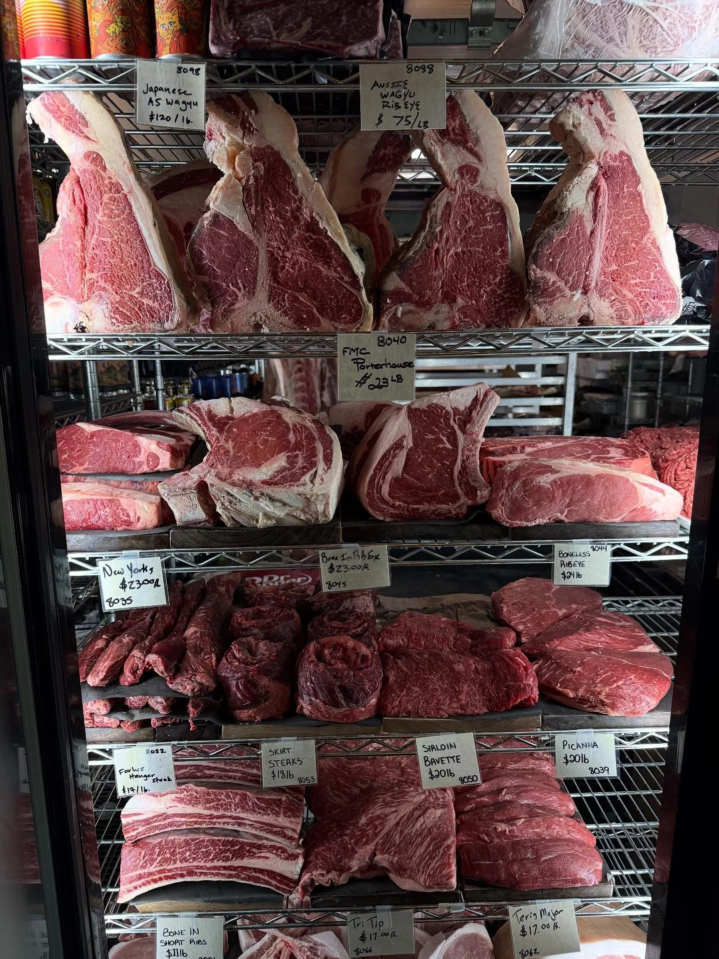 Forbes Meat Company displays of various cuts of beef in a refrigerated meat case, including ribeye, porterhouse, New York strip, sirloin, and flank steak.