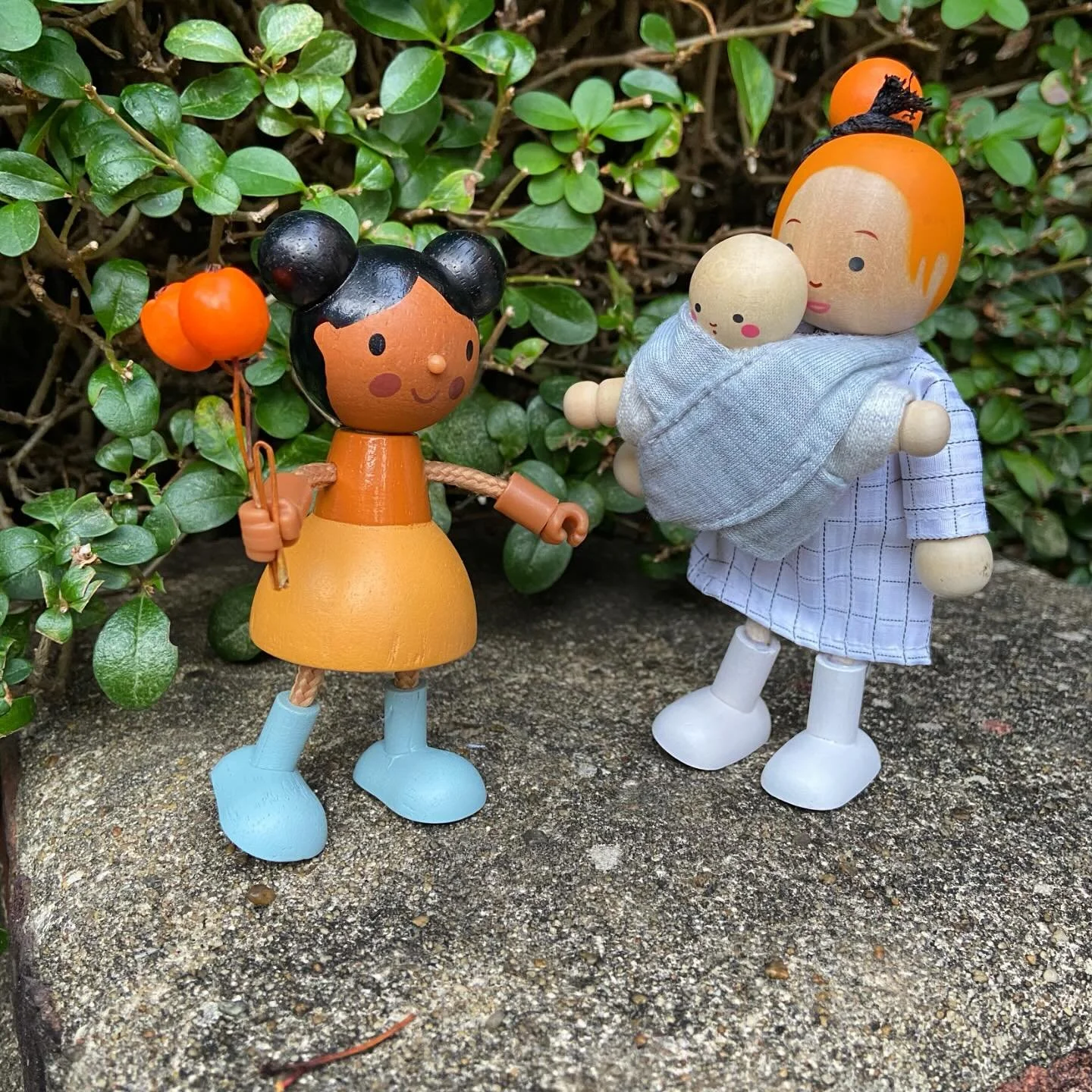 Through socializing with other children parents discover their children in new ways 🟠☀️
IMAGE DESCRIPTION: The image features a group of wooden dolls, including a mother and baby, set in an outdoor environment. They appear to be situated on the gro