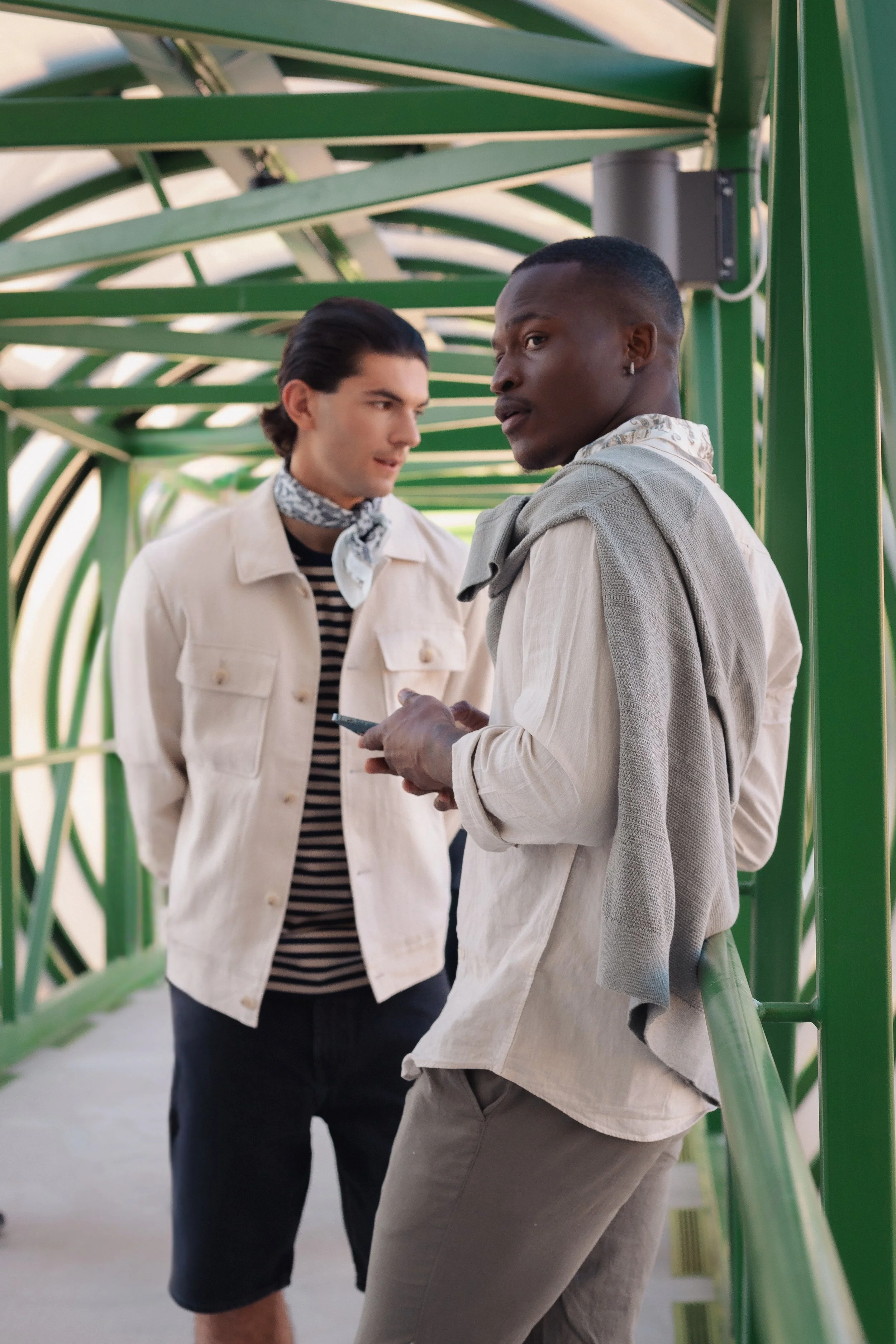 Two men dressed in light clothes posing in a green corridor