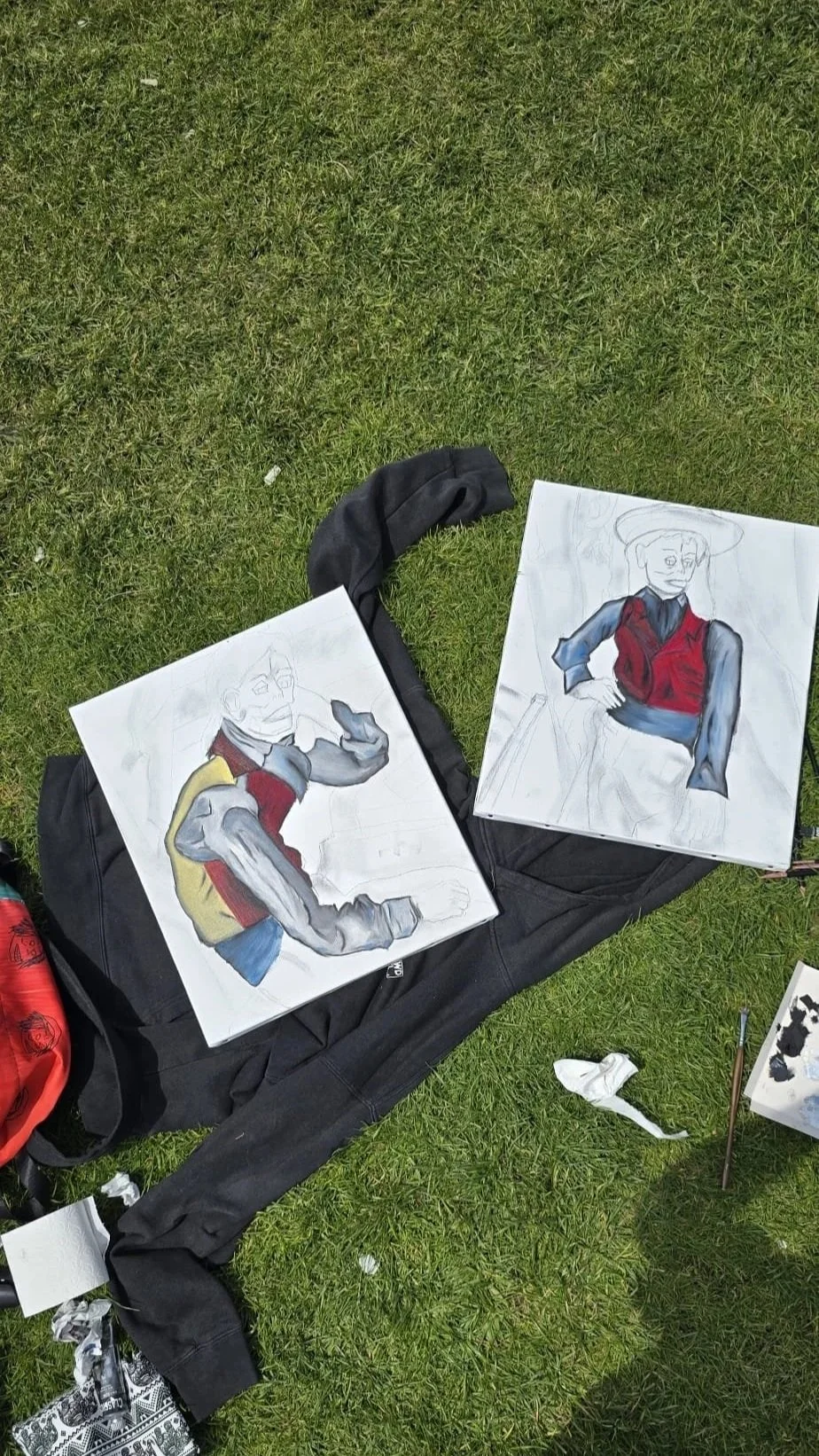 Two watercolor paintings on paper, depicting a stylized person in military or historical attire, resting on a black bag outdoors on green grass.