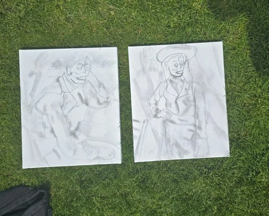 Two sketches of women in vintage clothing on white paper lying on grass, one with a hat and the other with glasses.