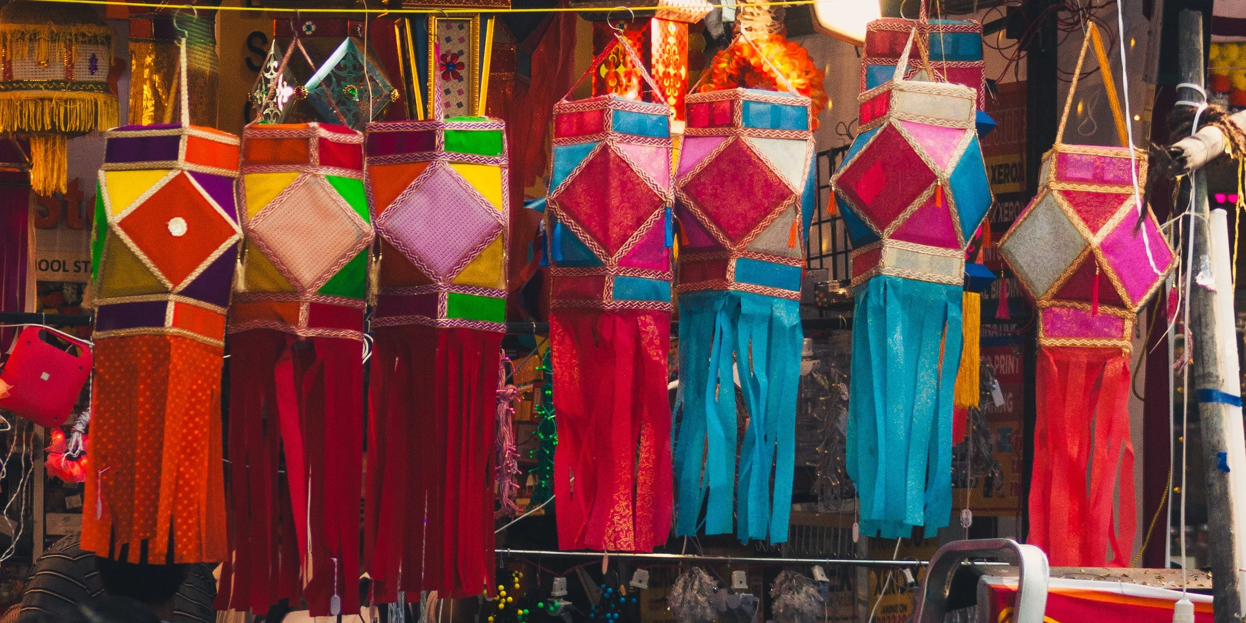 Colorful lanterns with tassels hanging at a market stall.