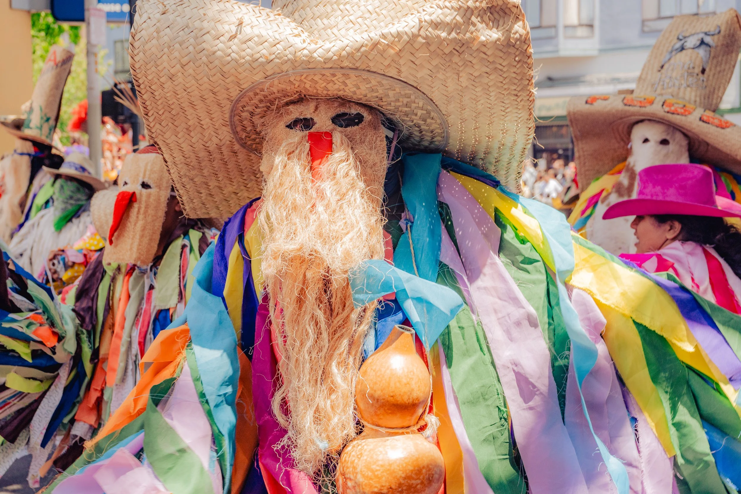 Colorful traditional Mexican costumes with large sombreros and masks at a festive celebration.