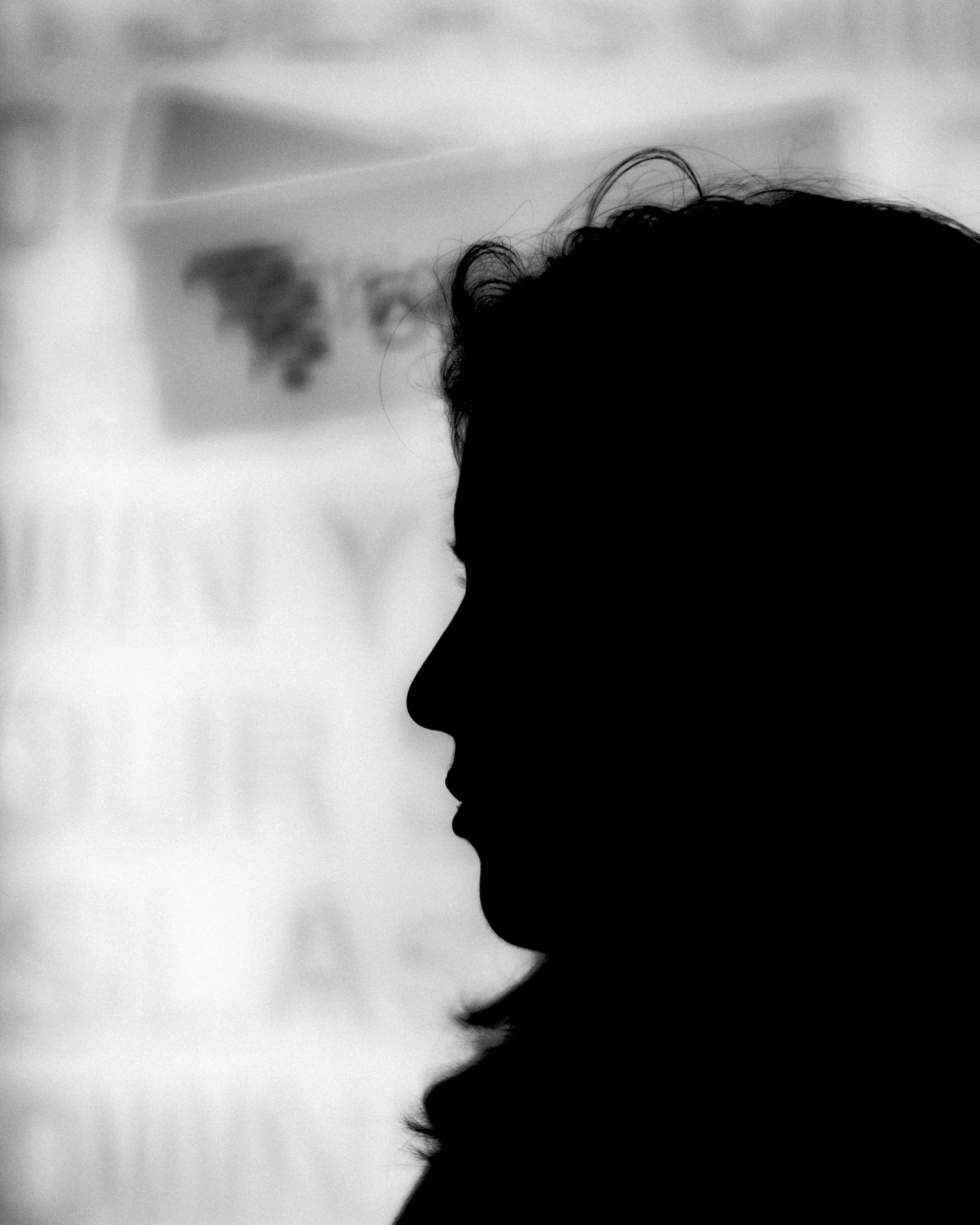 Silhouette of a person's profile in black and white, with a blurred background.