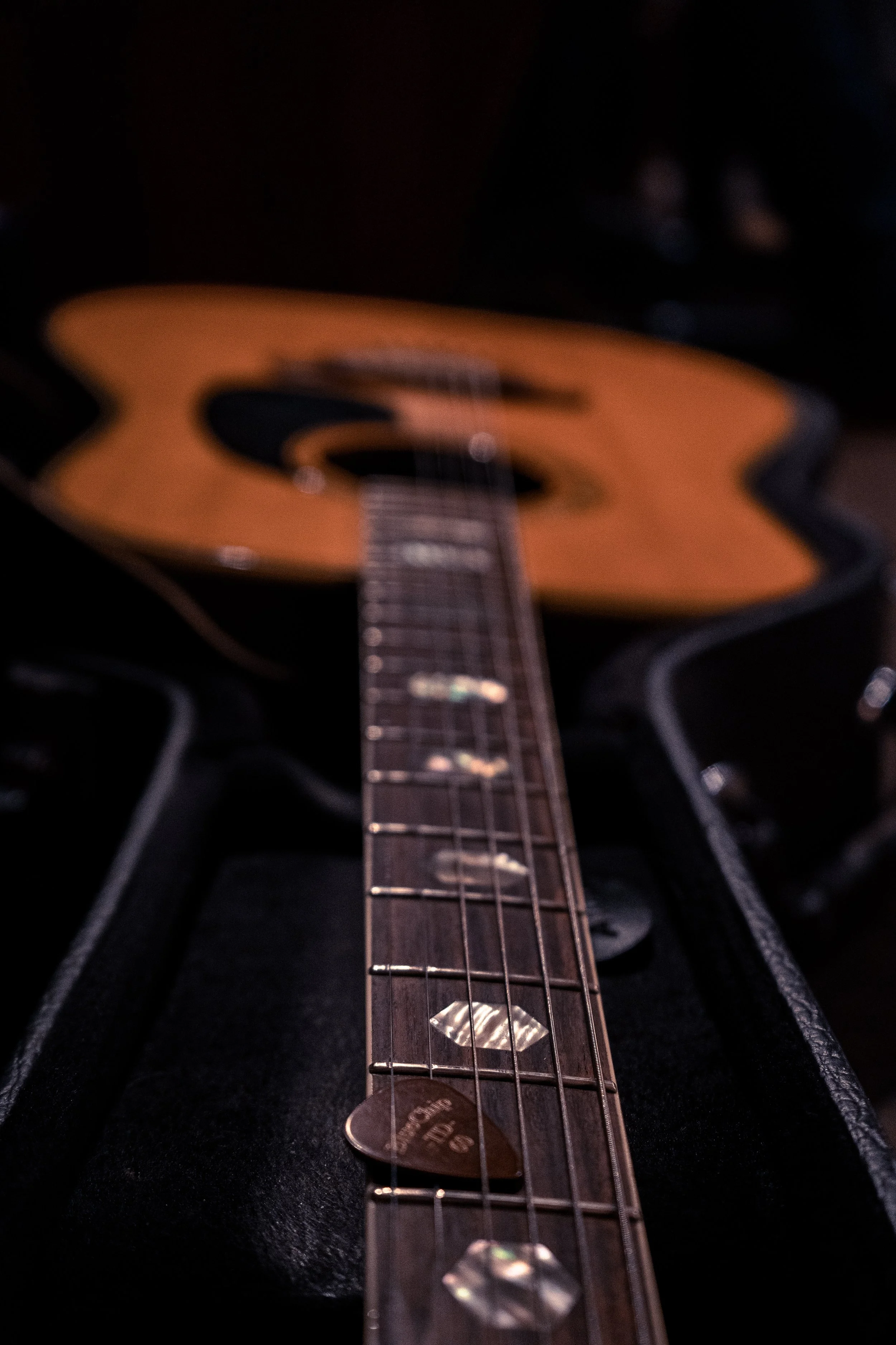 Close-up of an acoustic guitar in its open case, with the focus on the fretboard and strings.