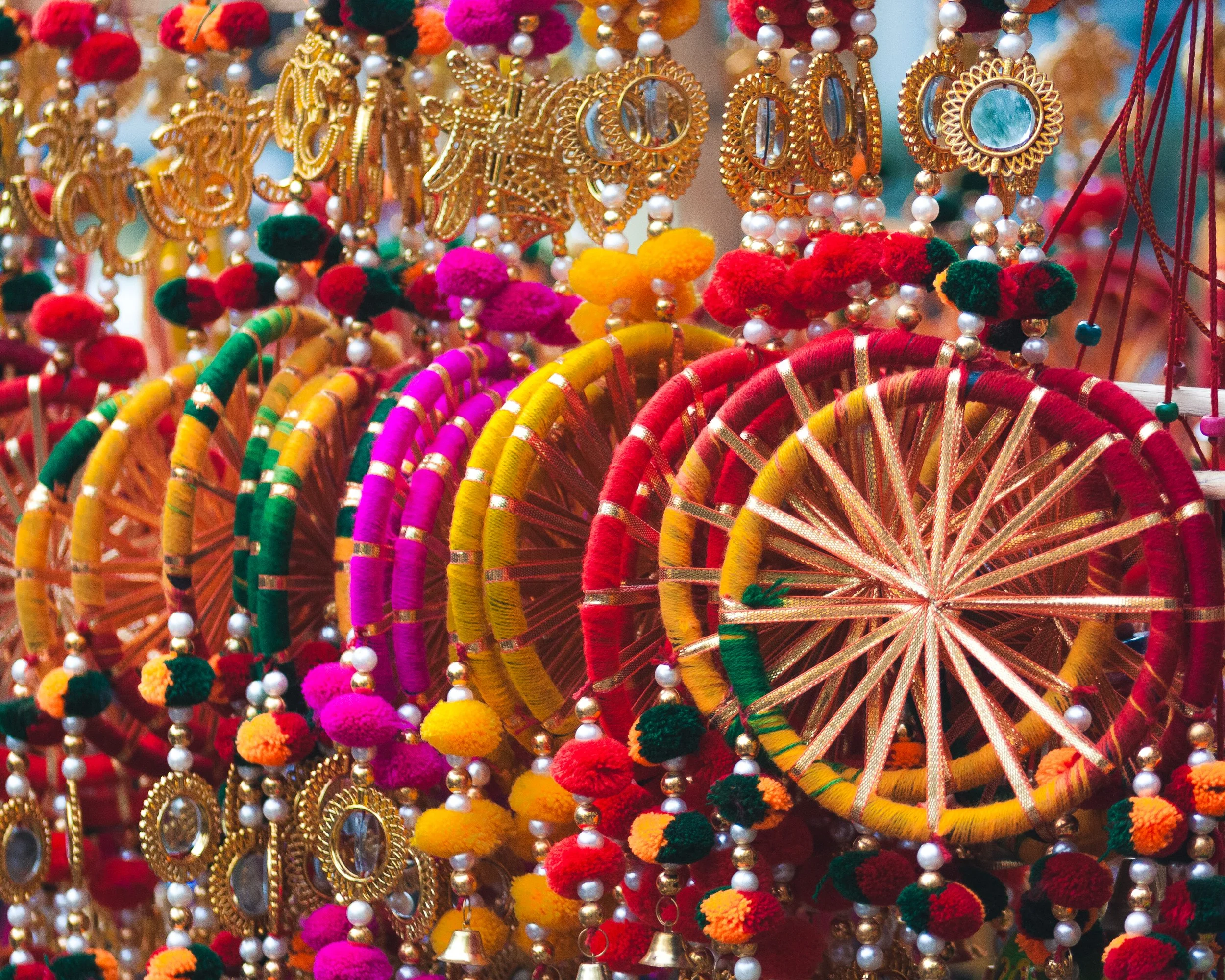 Colorful traditional Indian bangles, earrings, and jewelry with pom-poms and beads on display.