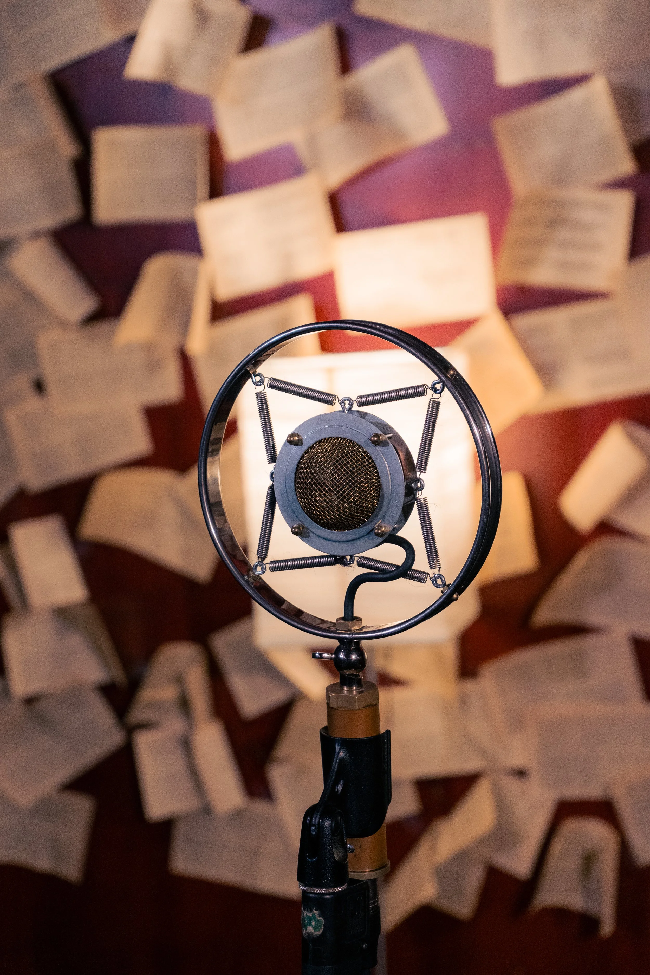 Close-up of a vintage studio microphone with open book pages scattered in the background.