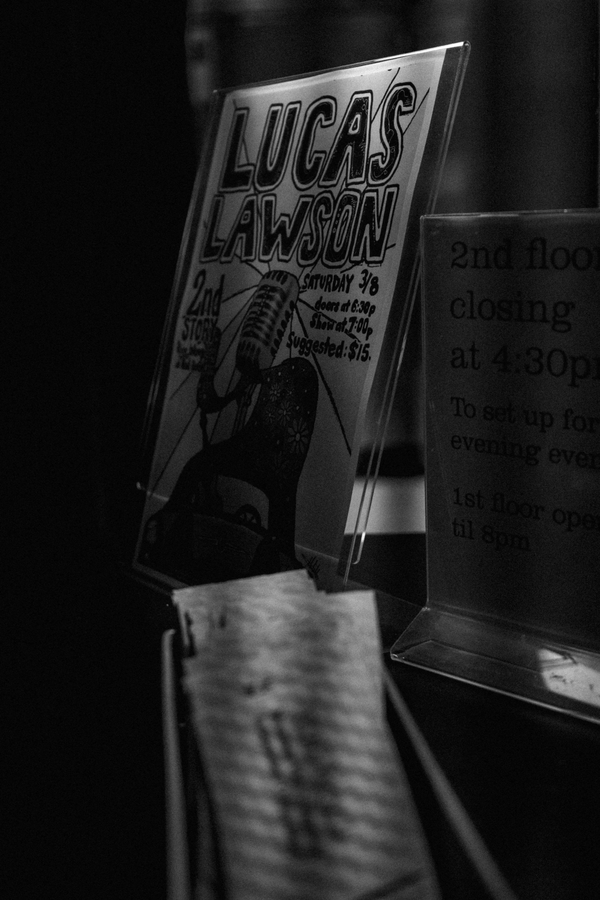 Black and white photo of a concert flyer for Lucas Lawson with event details and an illustration of a vintage microphone.