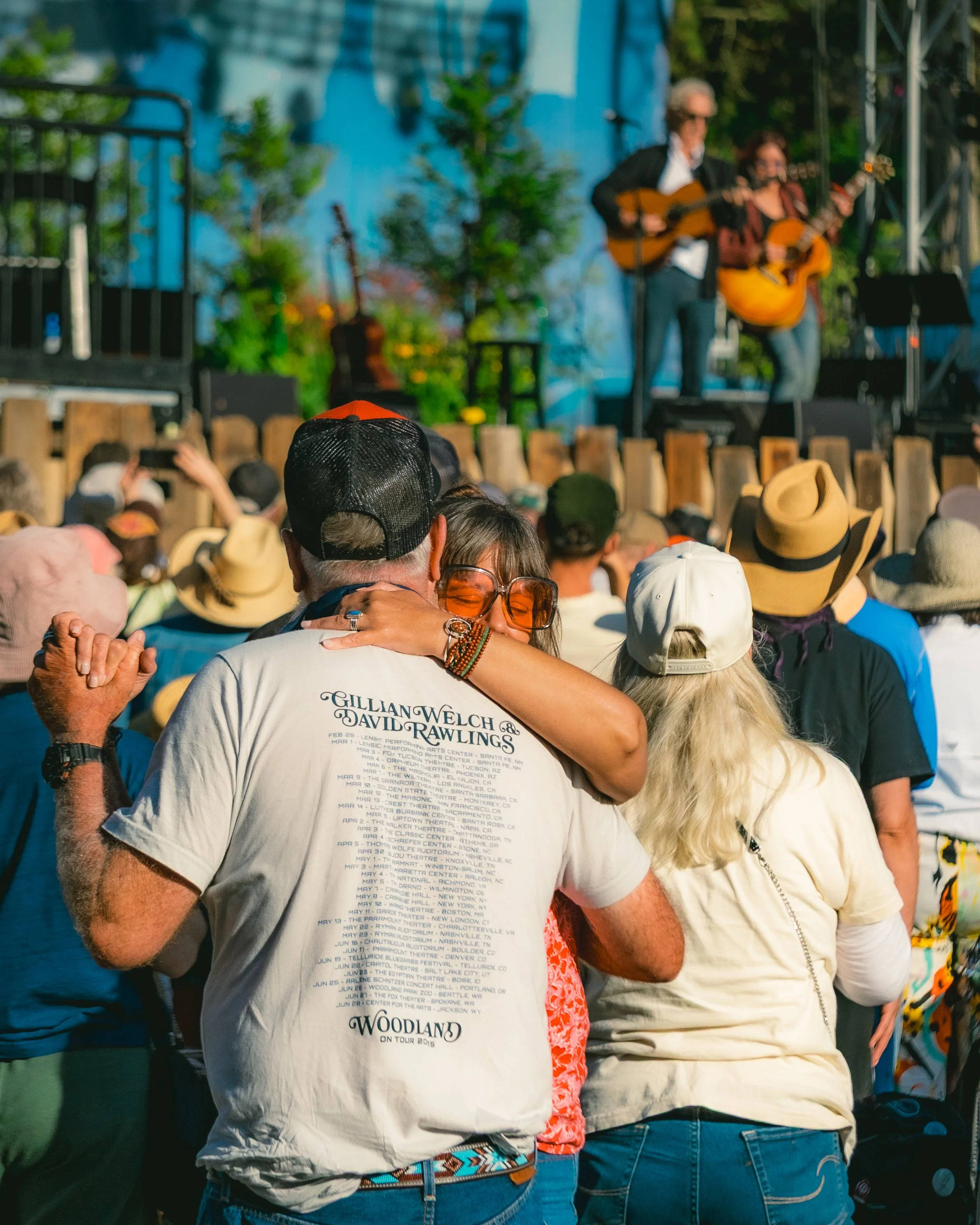 People watching a live outdoor concert with musicians playing guitars on stage.