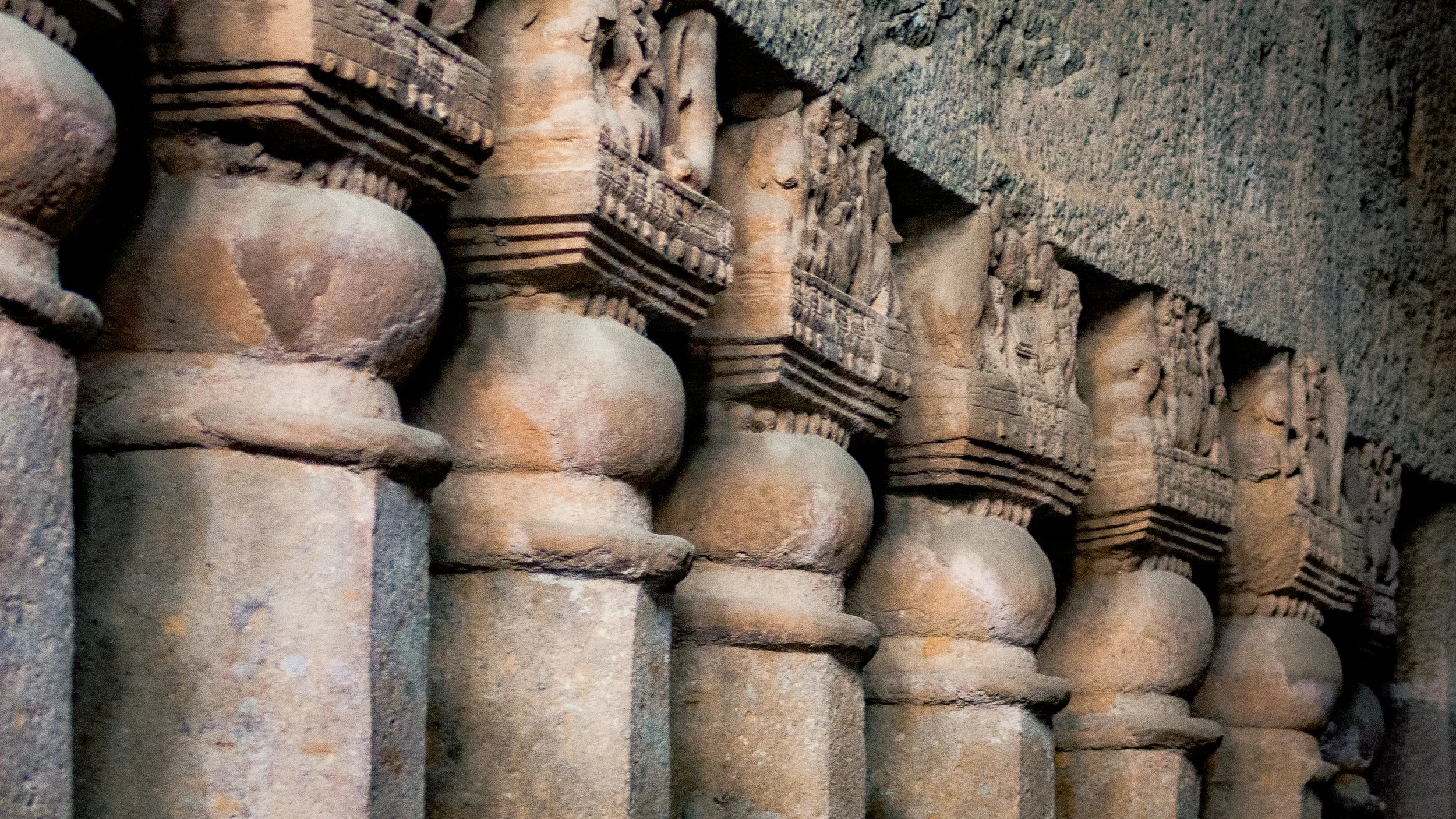 Ancient stone columns with intricate carved capitals, part of historical religious or architectural site.