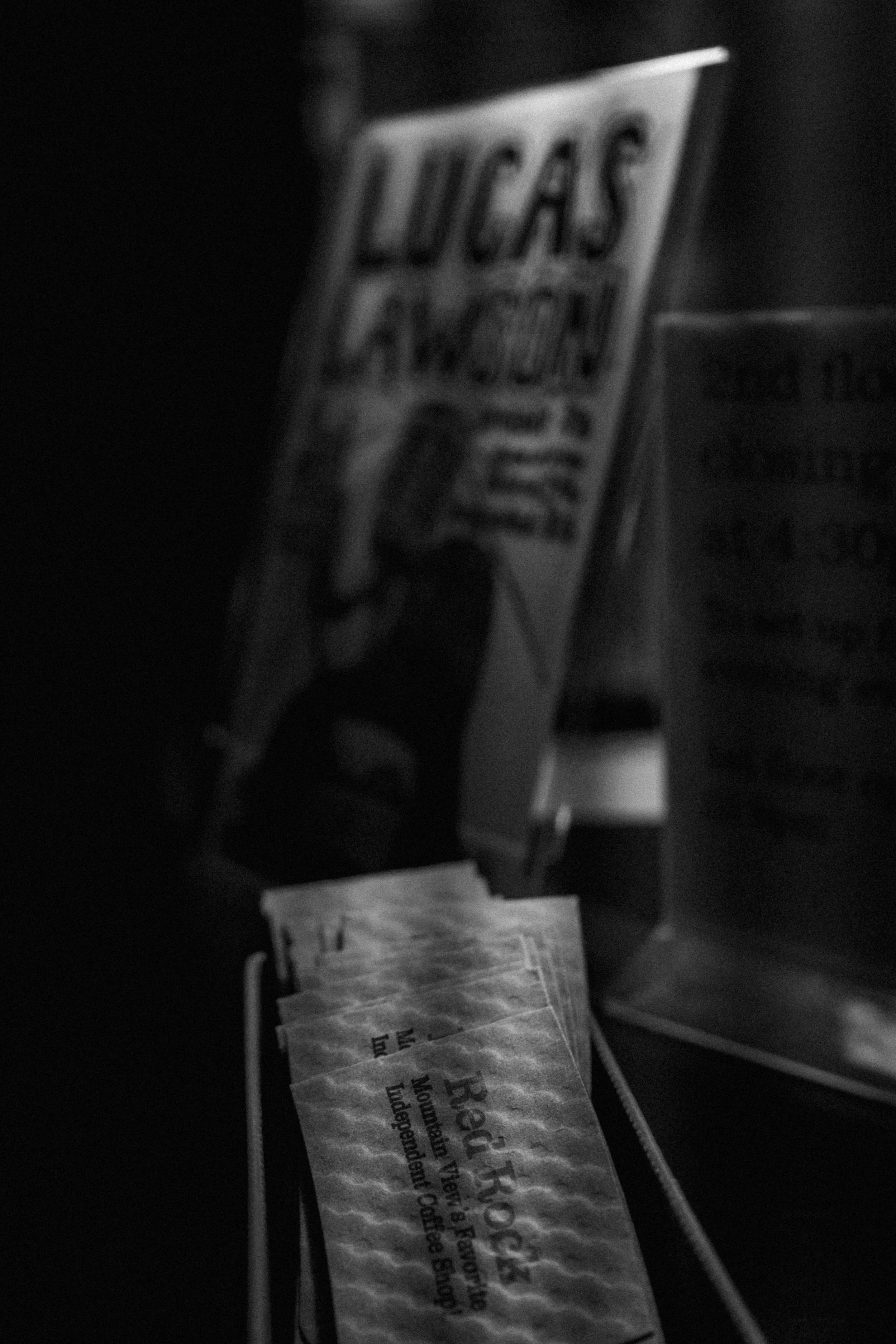Black-and-white photo of a Lucas Oil Racing sticker with a person holding a wrench, and several small paper pieces with the letters "Heat" visible.