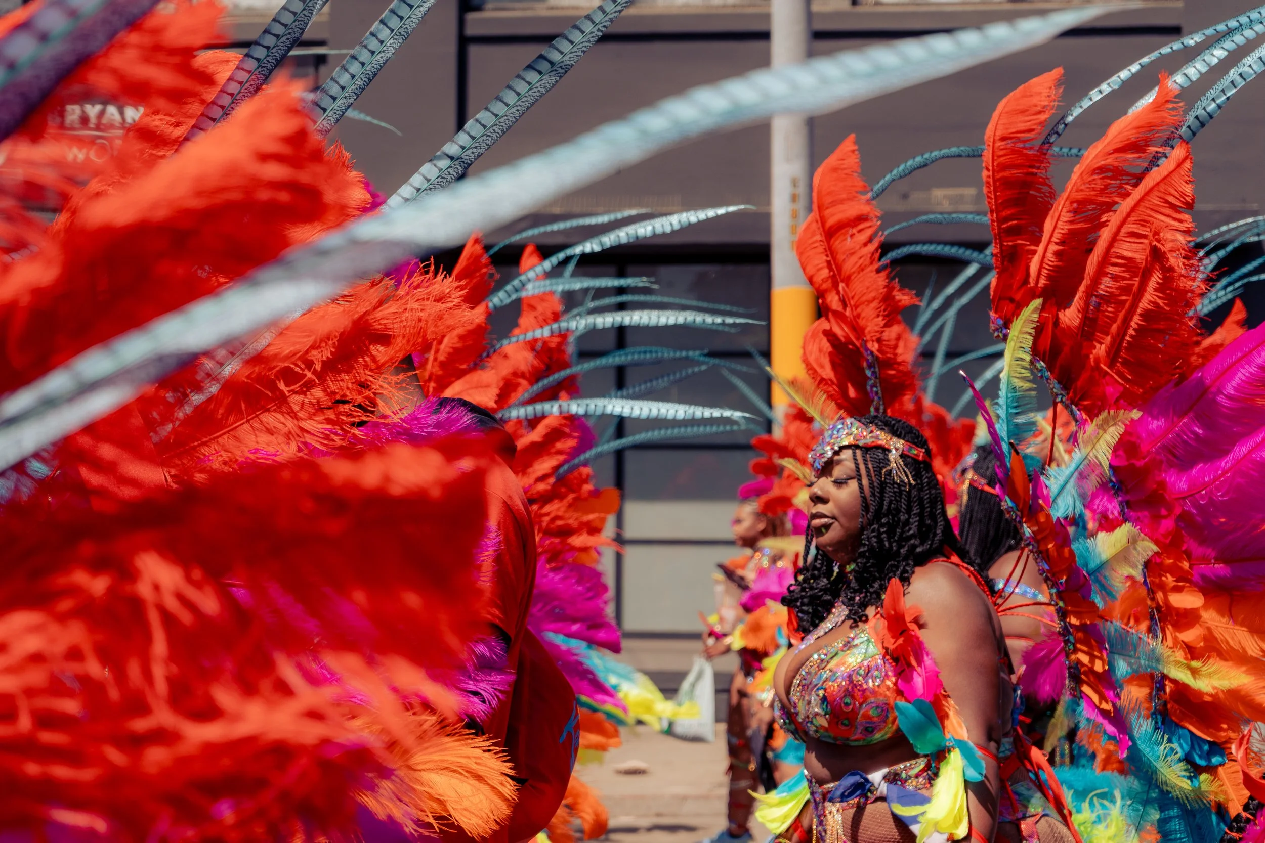Women dressed in colorful costumes with elaborate feather headdresses participating in a parade or carnival.