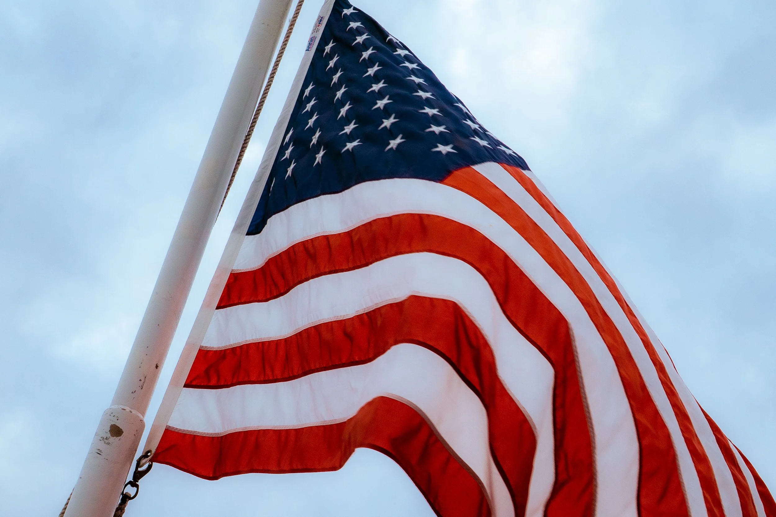 American flag flying against a cloudy sky.