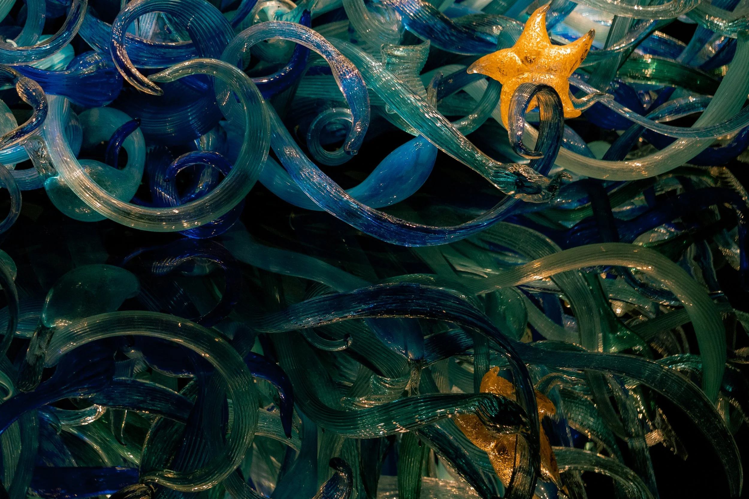 Colorful glass art with swirling blue, green, and yellow glass pieces interwoven.