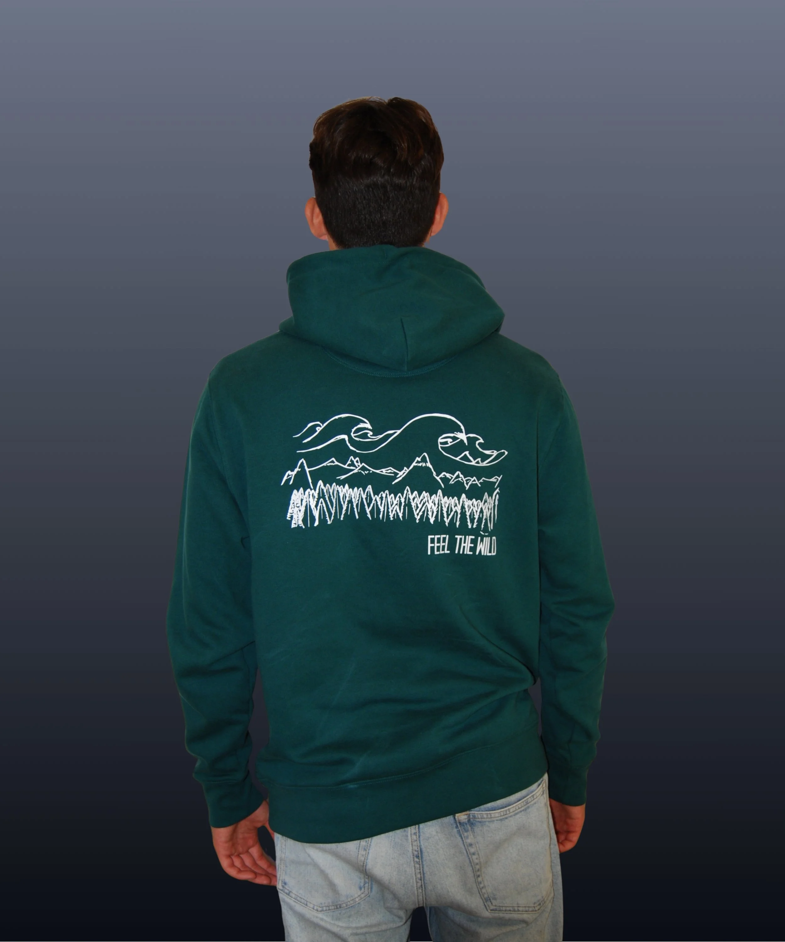 Una persona con una felpa verde scuro che ha sul retro un disegno di montagne, alberi e volantini con la scritta 'FEEL THE WILD'.