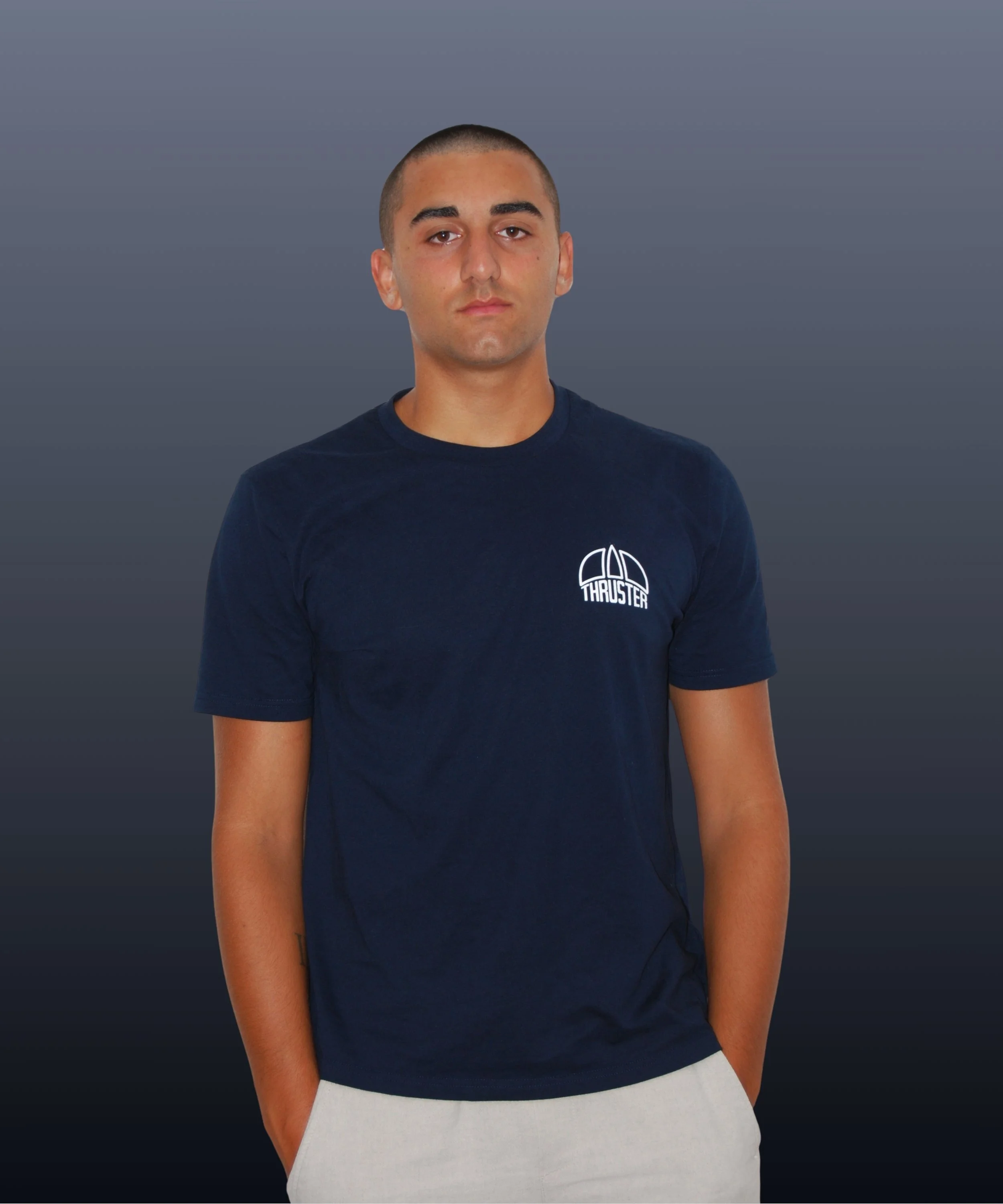 Ragazzo giovane con pelle chiara, capelli corti e scuri, indossa una maglietta blu con logo Thruster, sfondo grigio scuro.