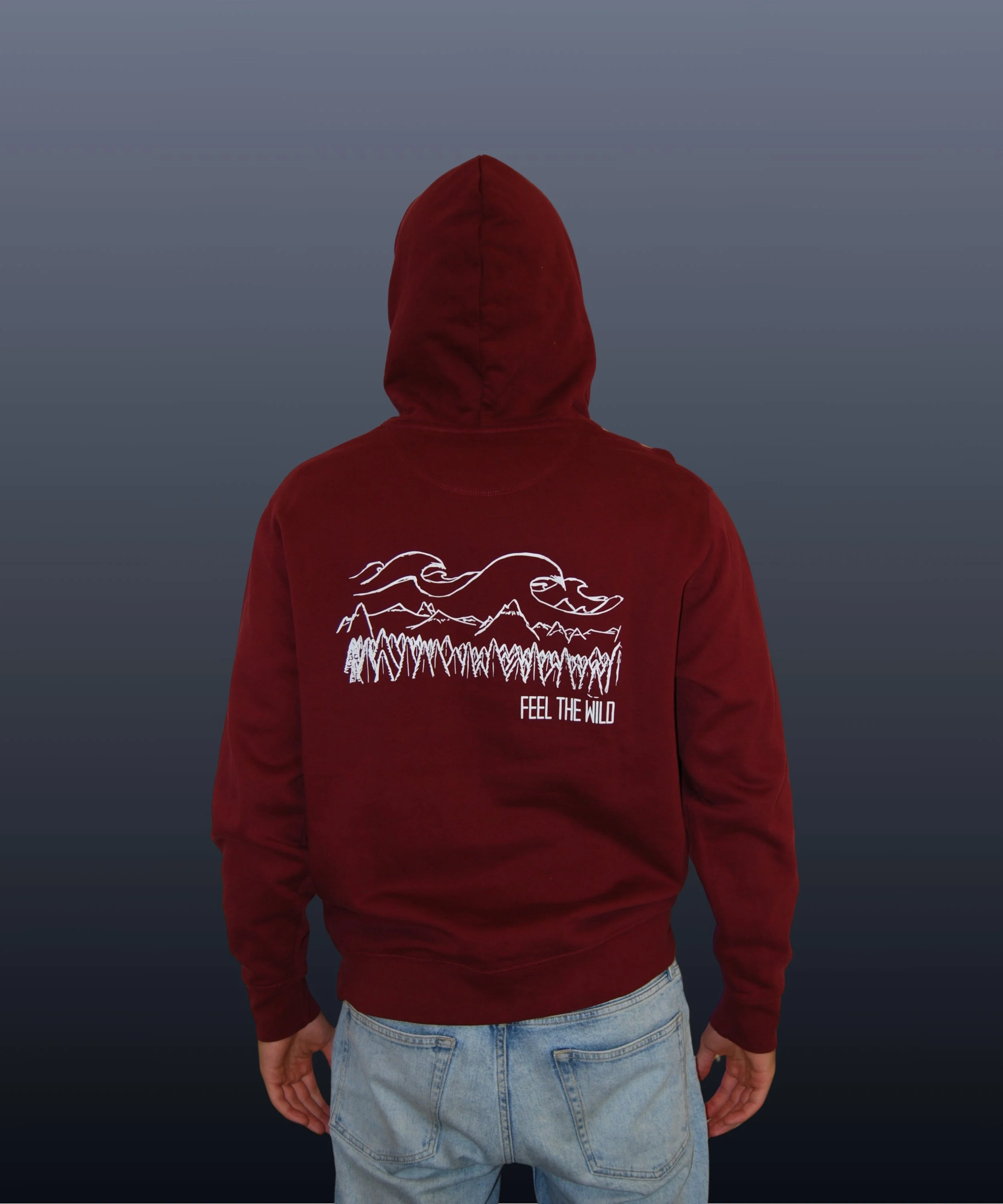 Persona vista di schiena indossa felpa rossa con grafica di montagne, foresta e nuvole, e la scritta "Feel the Wild".