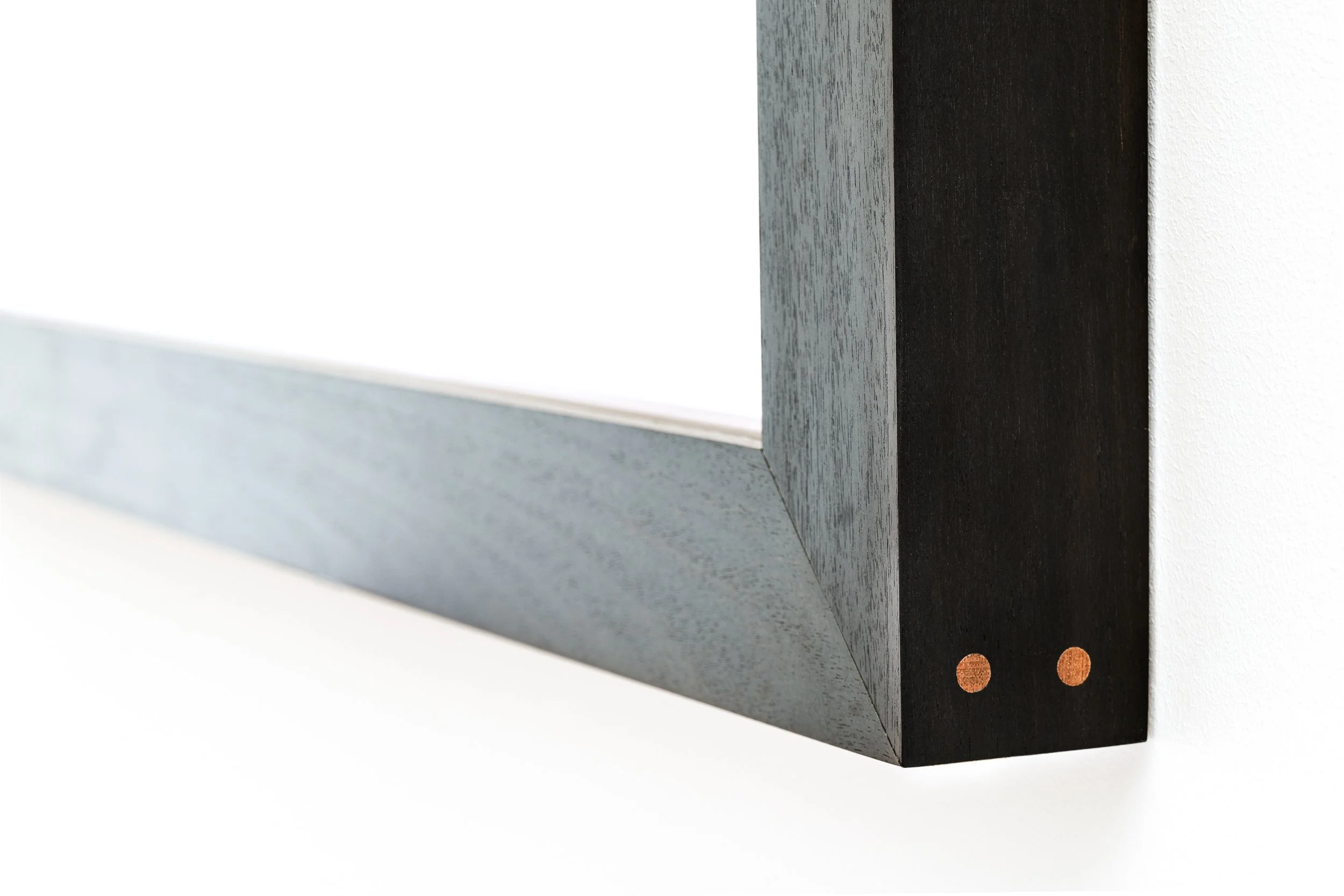Close-up of a black and gray wooden object with a smooth finish, set against a plain white background.
