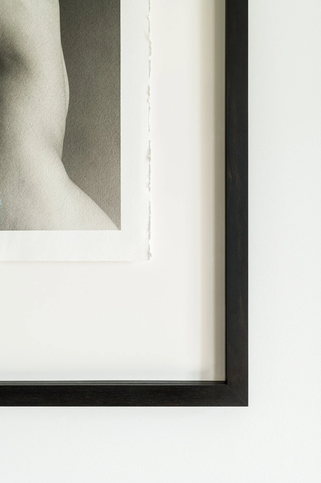 Minimalist artwork with black and white abstract shapes framed in black, displayed on a white wall.