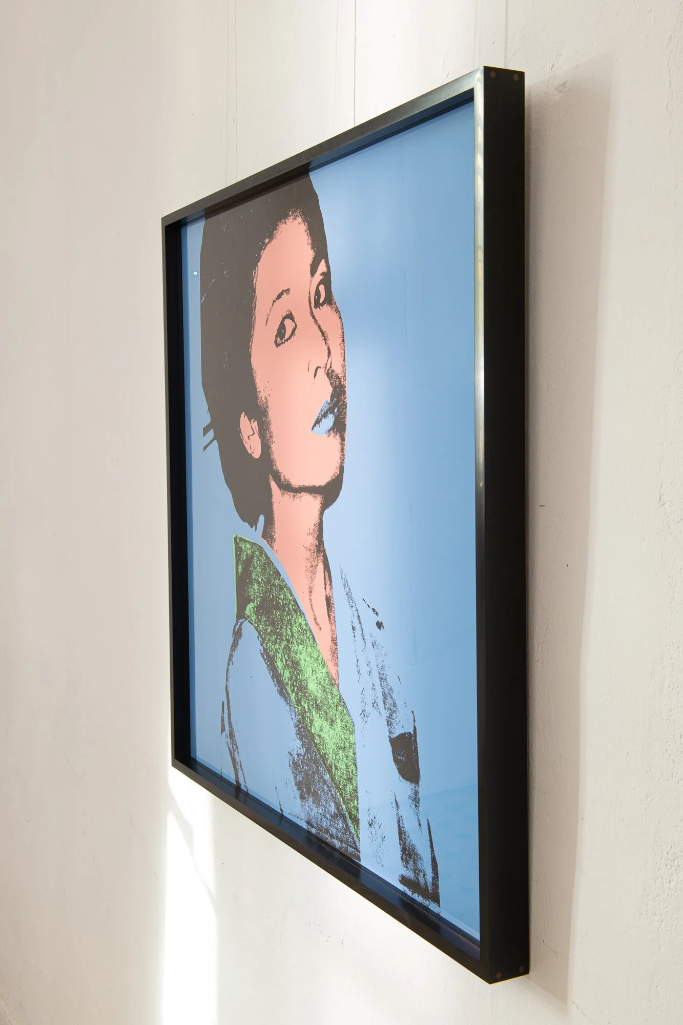 Grafika „Kimiko” Andy'ego Warhola w ręcznie wykonanej ramie z hebanu gabońskiego, sfotografowana pod kątem, prezentowana na jasnej ścianie.