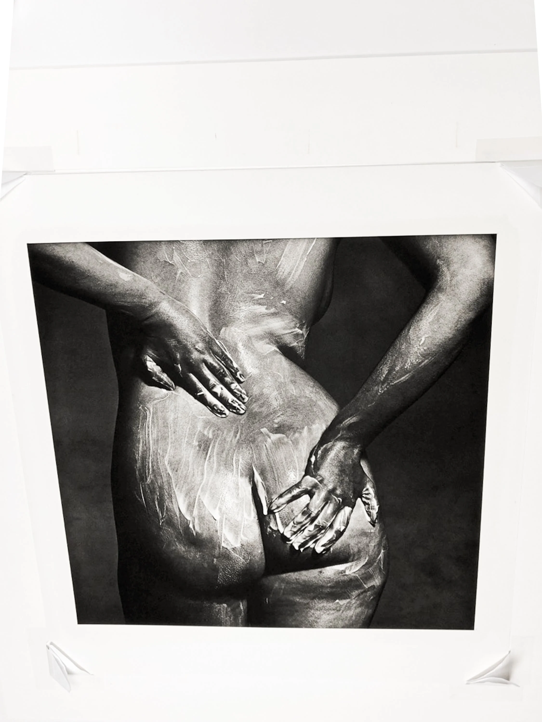 Black and white photograph of a sculpture featuring intertwined male and female bodies with visible muscular and skeletal features.