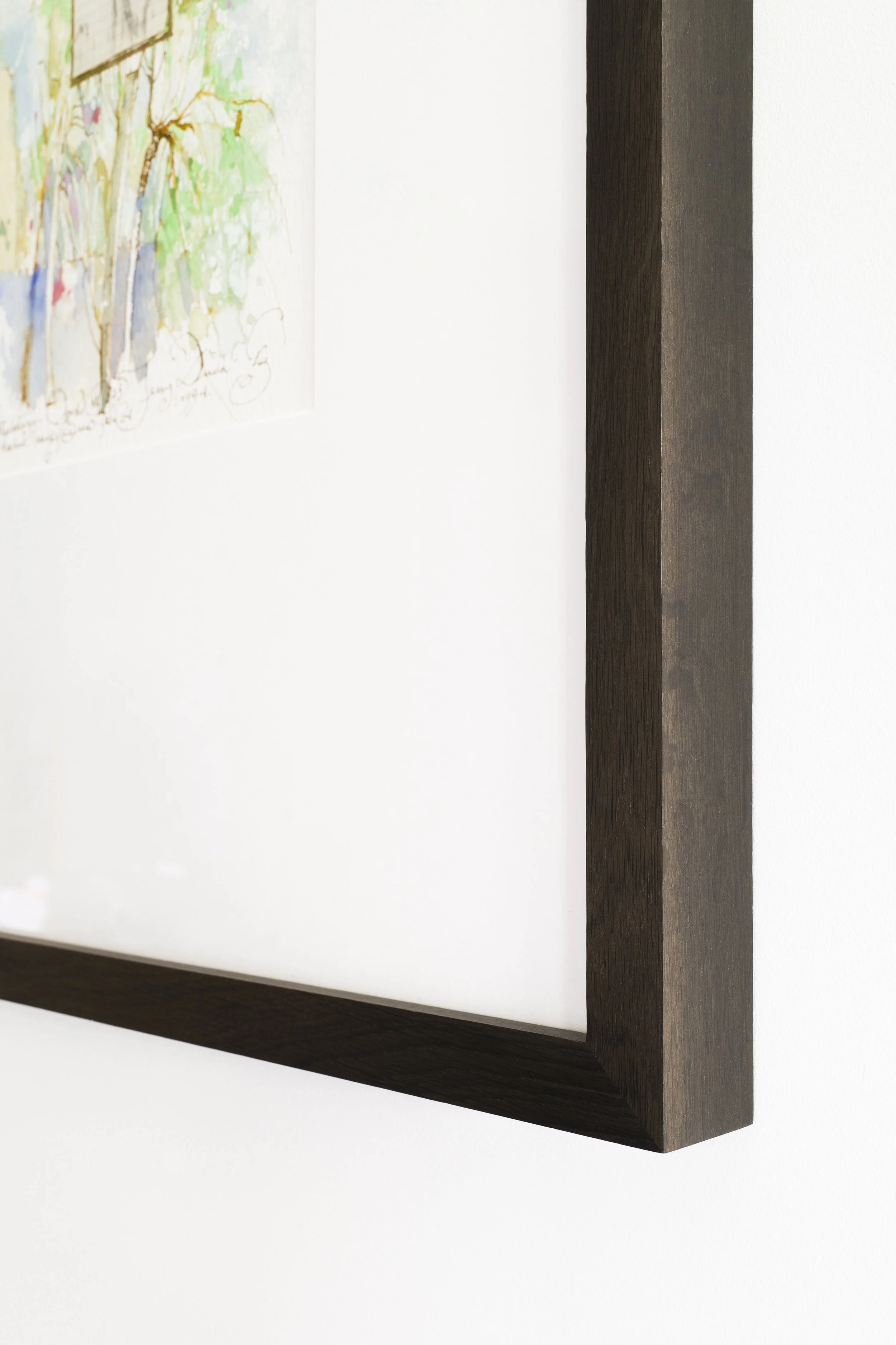 Close-up of a dark wooden corner of a picture frame on a white wall.