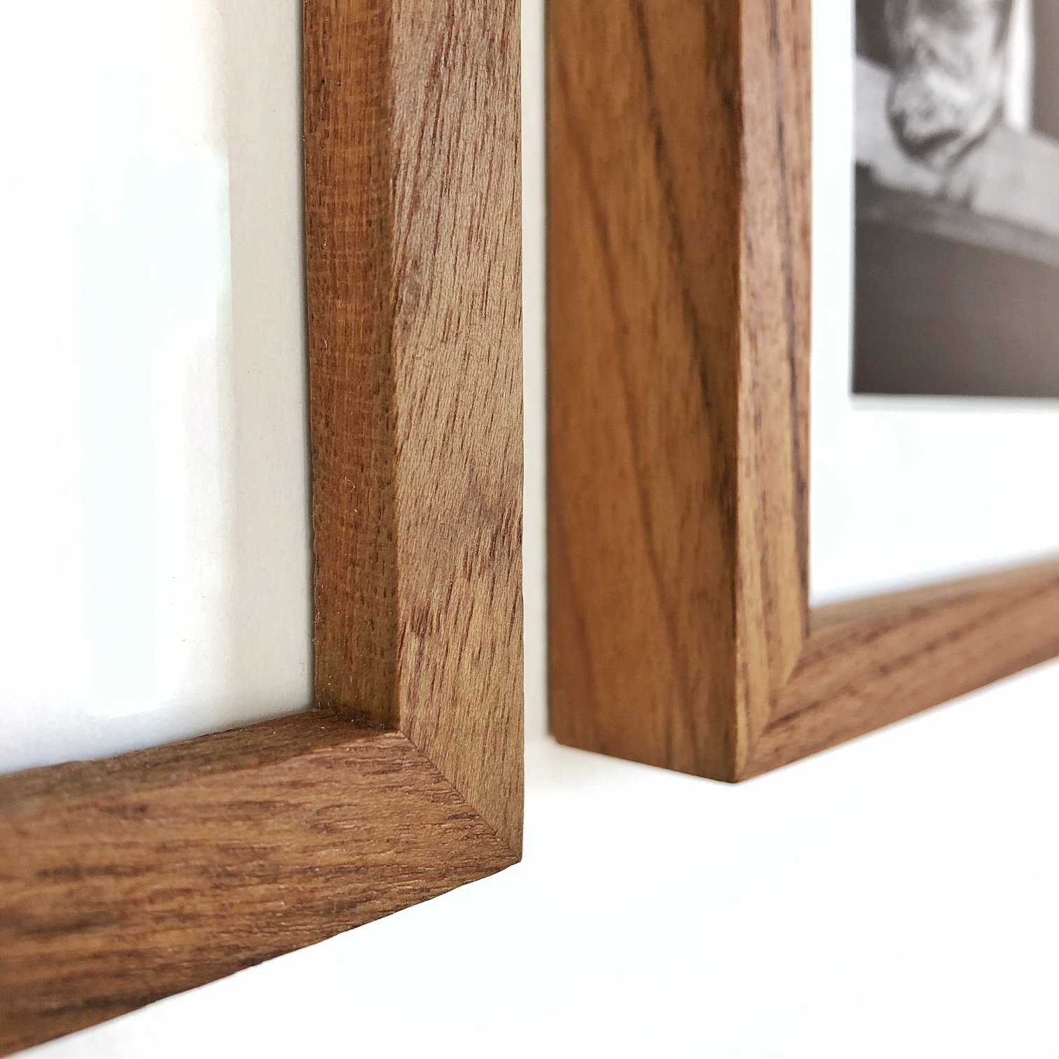 Close-up of a wooden picture frame with a notice board inside, mounted on a white wall.