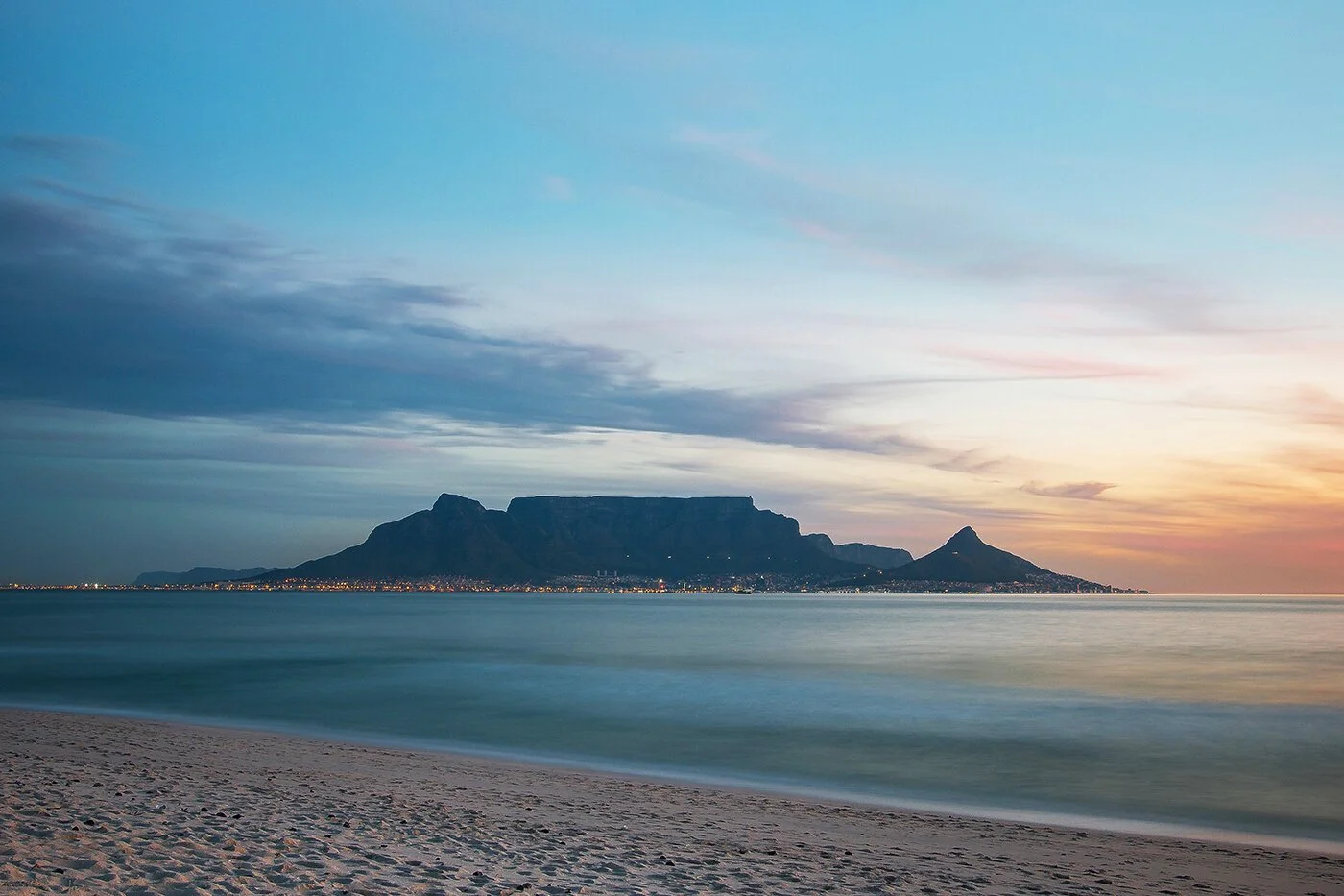 Scenic view of Table Mountain and Lion's Head at sunset with a sandy beach and calm ocean in the foreground, Cape Town, South Africa. Kinetic Catamarans commissioning and sea trials.