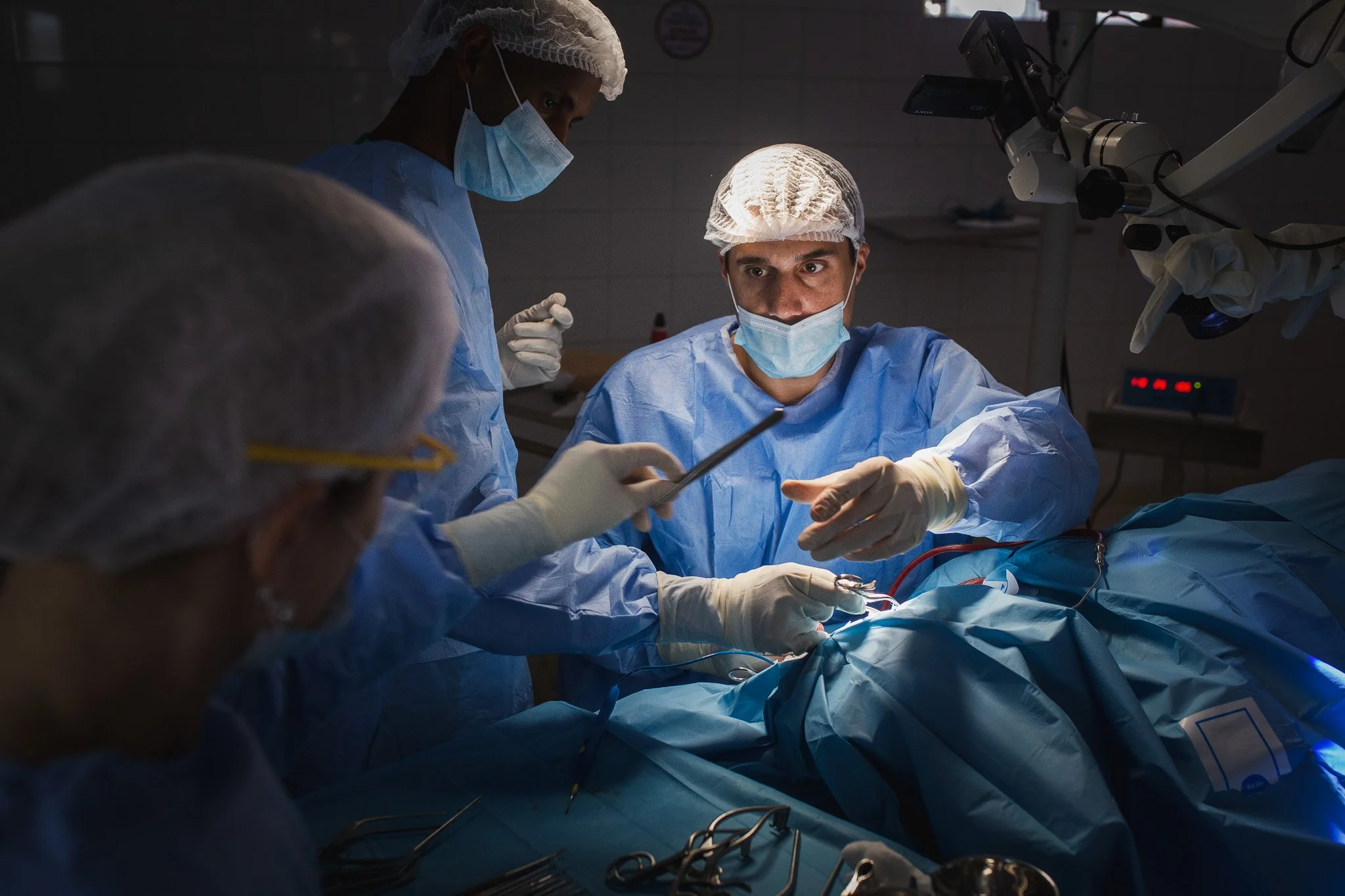 Medical team performing surgery in an operating room, wearing protective gear and masks.