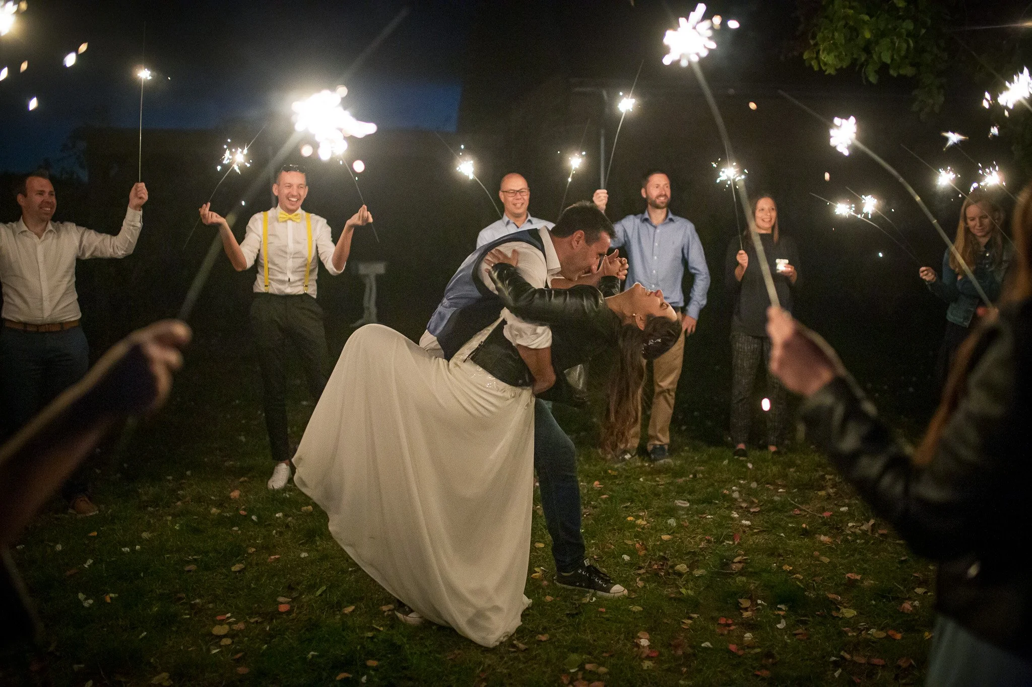 Wedding reception in the evening with a bride and groom dancing while friends hold sparklers around them.