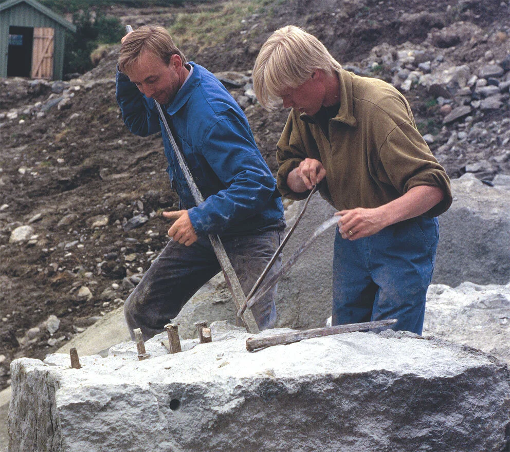 SPLITTING: Steinhoggerne Atle Elverum og Henning Grøtt deler opp blokk ved hjelp av kiler med blekker i kleberbruddet på Bubakk ved Kvikne i 1995. Dette var et av de aller siste steinuttakene i bruddet. Nå forvitrer steinen de tok ut… Foto: Per Stor…