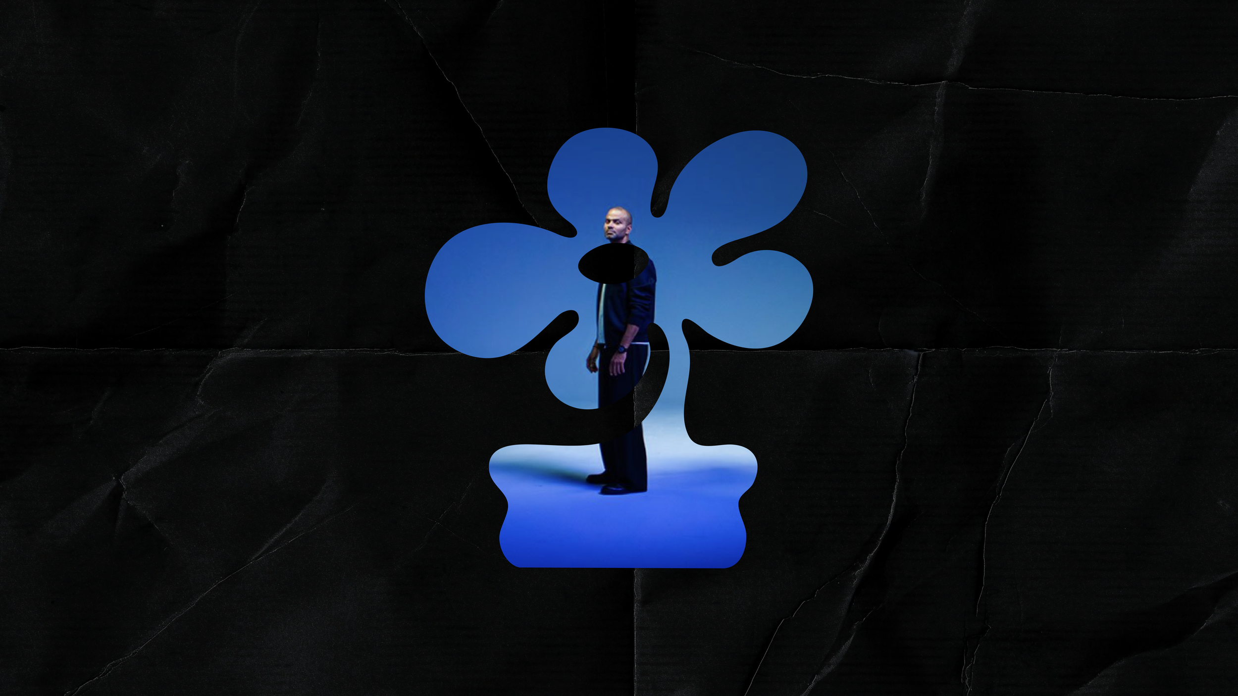 A cutout of a man's photo on a blue background shaped like a petal, set against a dark wall.