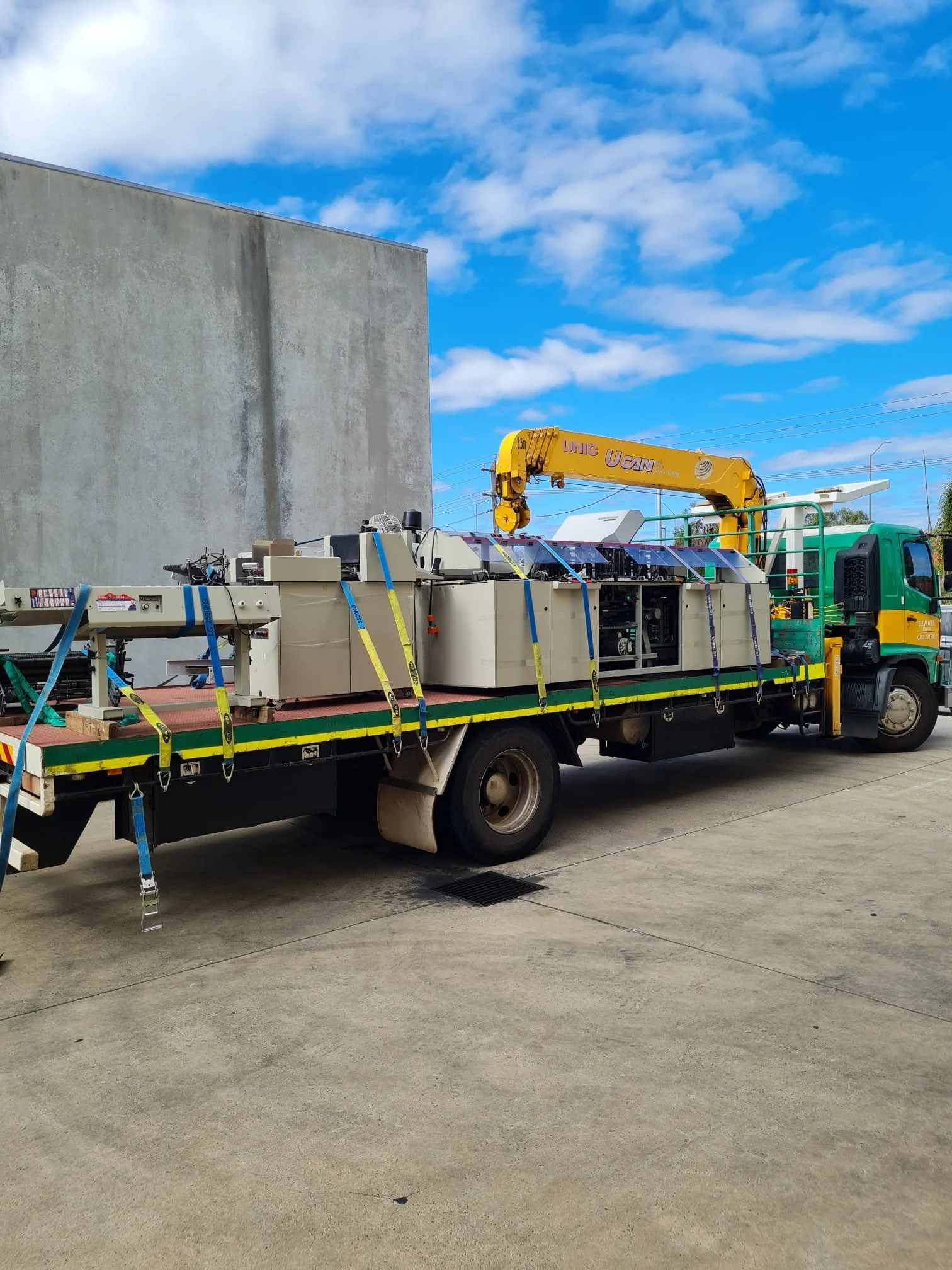 Picture of a Green and Gold Hiab Truck with a full 5tonne load on the 7.3m tray of a lathe machine in Perth