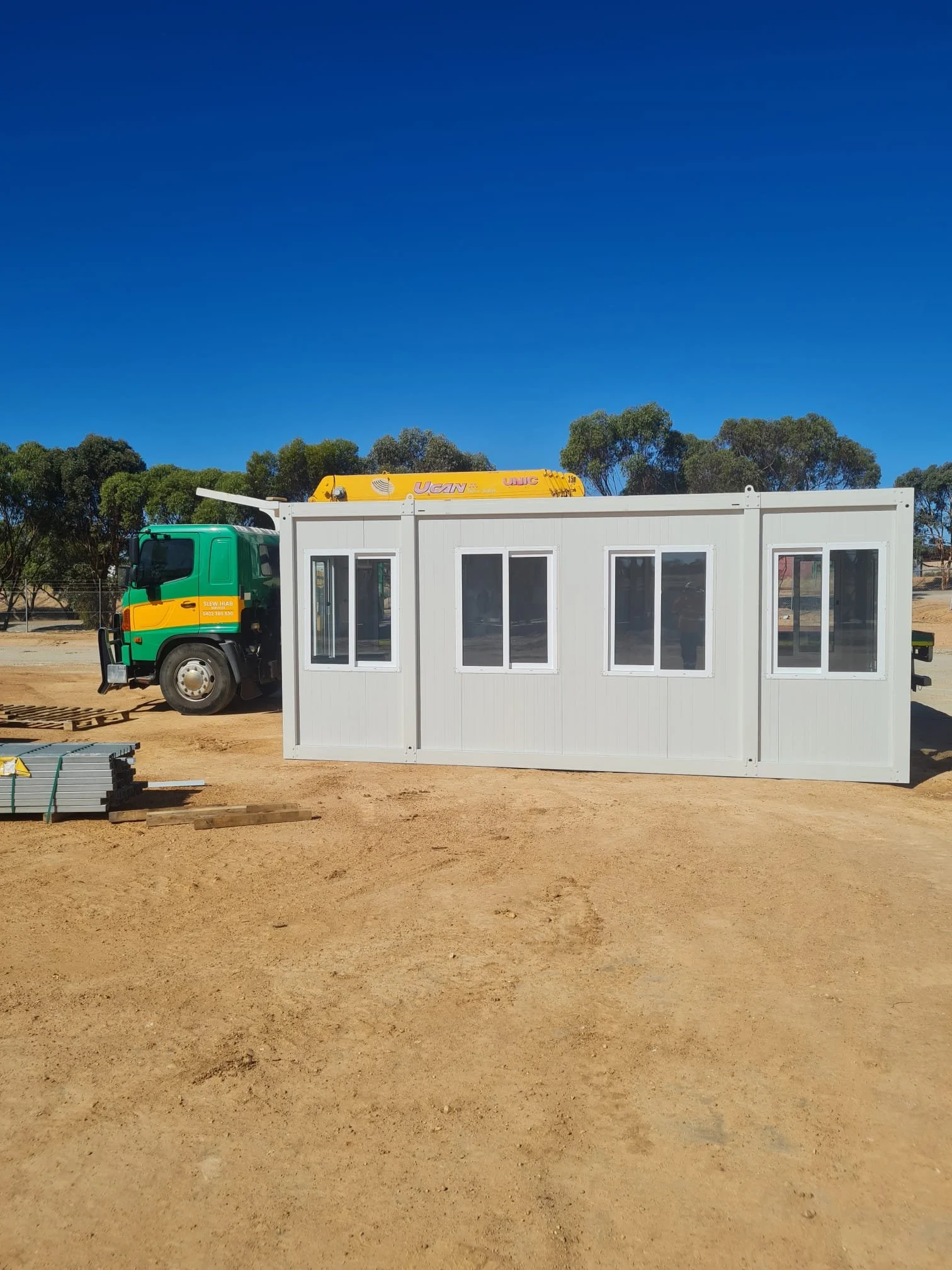 picture shows a Greens Hiab truck unloading a sit office to a Perth mining site using the crane