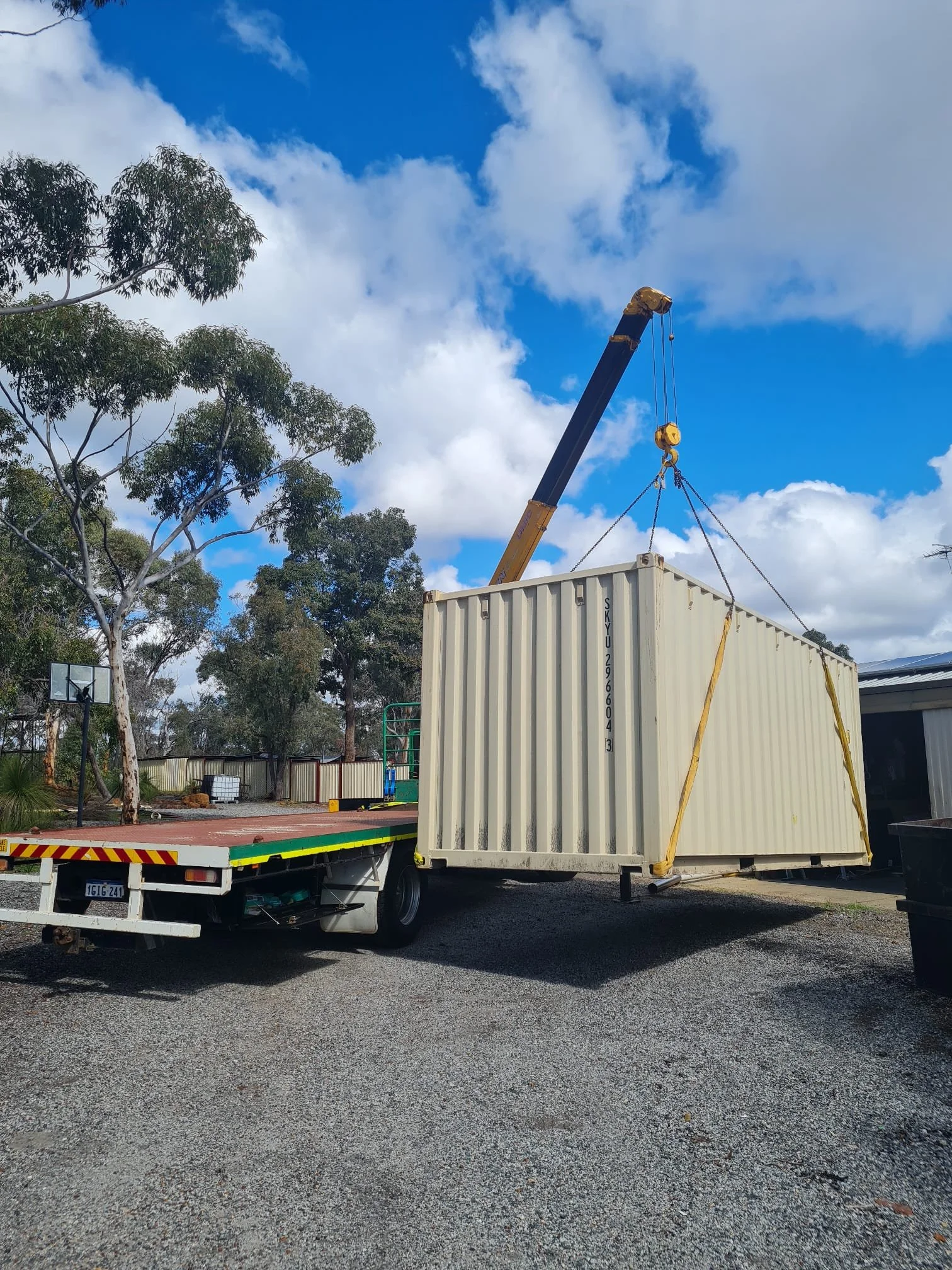 Picture is of a Greens Hiab truck lifting a 20ft sea container off the hiab container transport truck and into a yard in Perth
