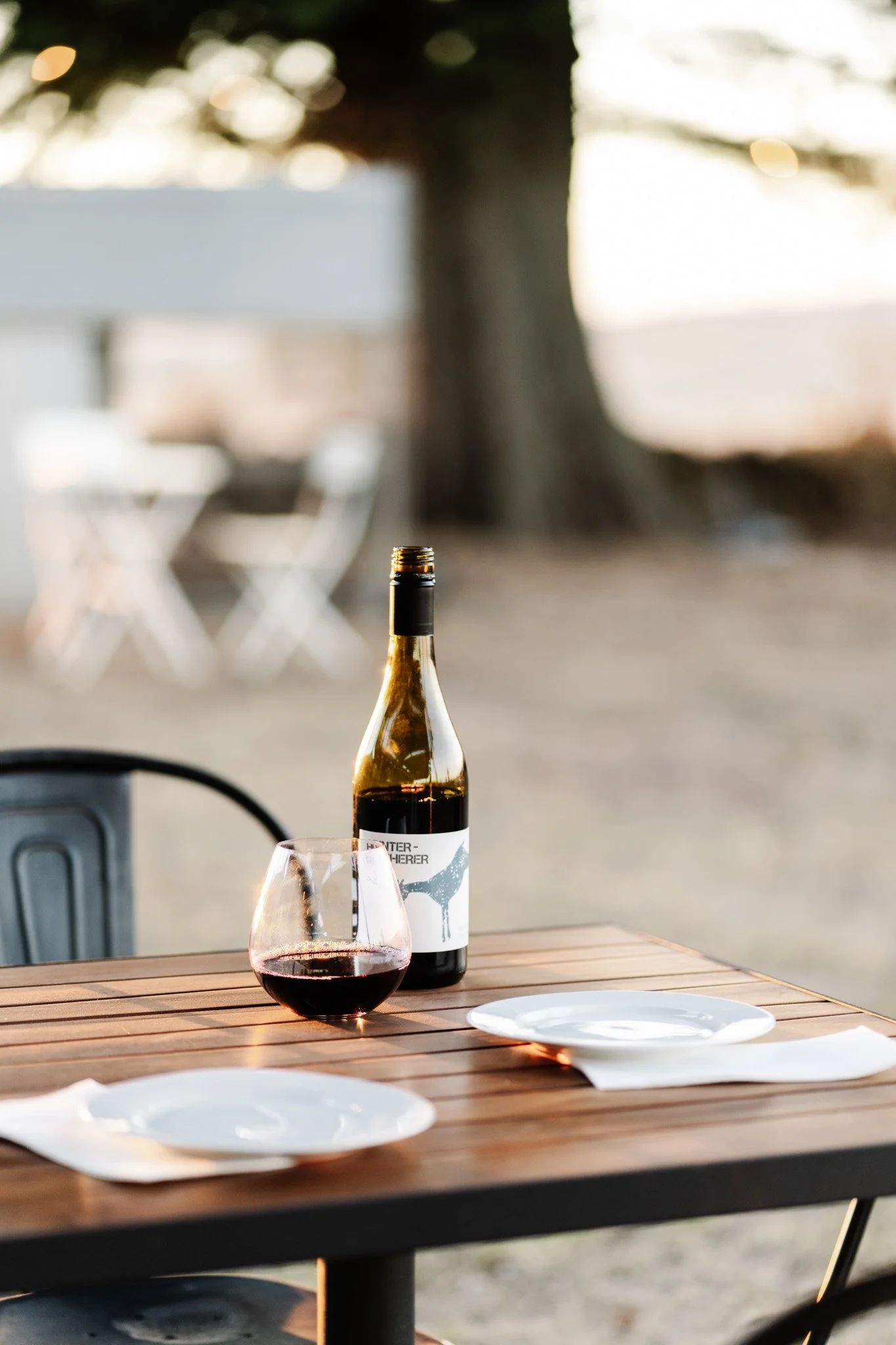 Red wine on table in glass with bottle behind it, at sunset