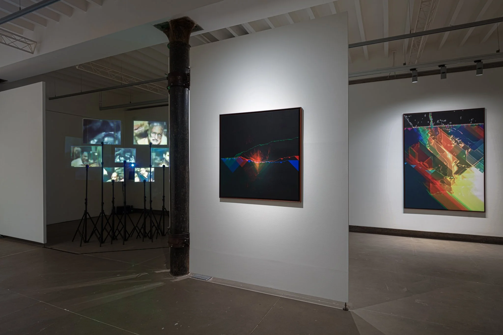 Art gallery with abstract digital paintings on white walls and multimedia installation with screens showing video portraits, industrial pipe in the foreground, and gallery lighting.