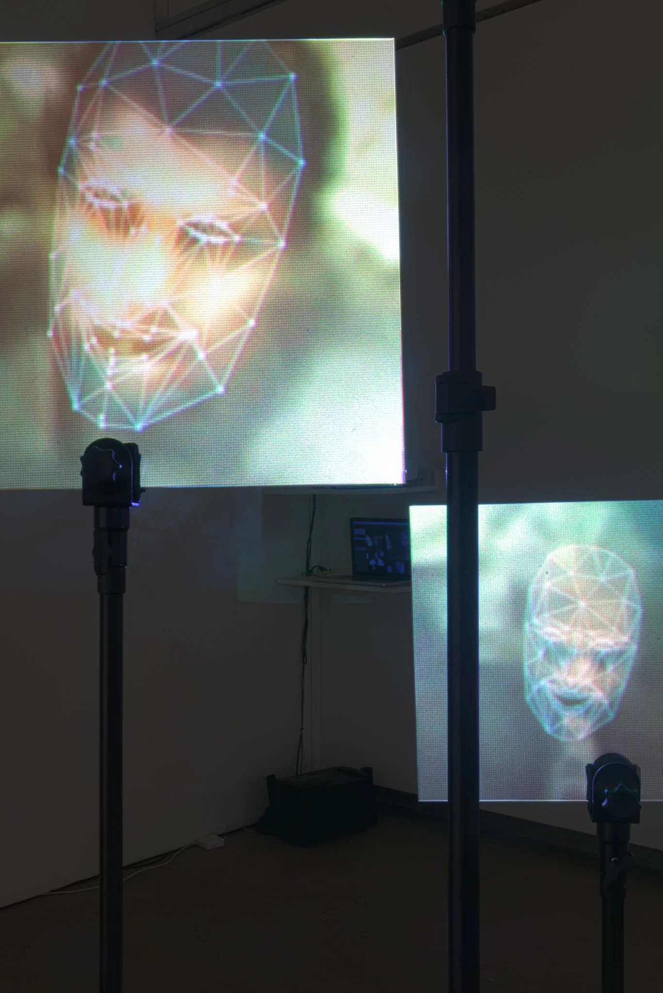 An art installation with digital face projection and lighting equipment in a gallery setting. Digital Art