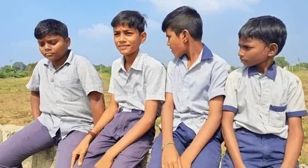 Four boys in uniform on a wall.