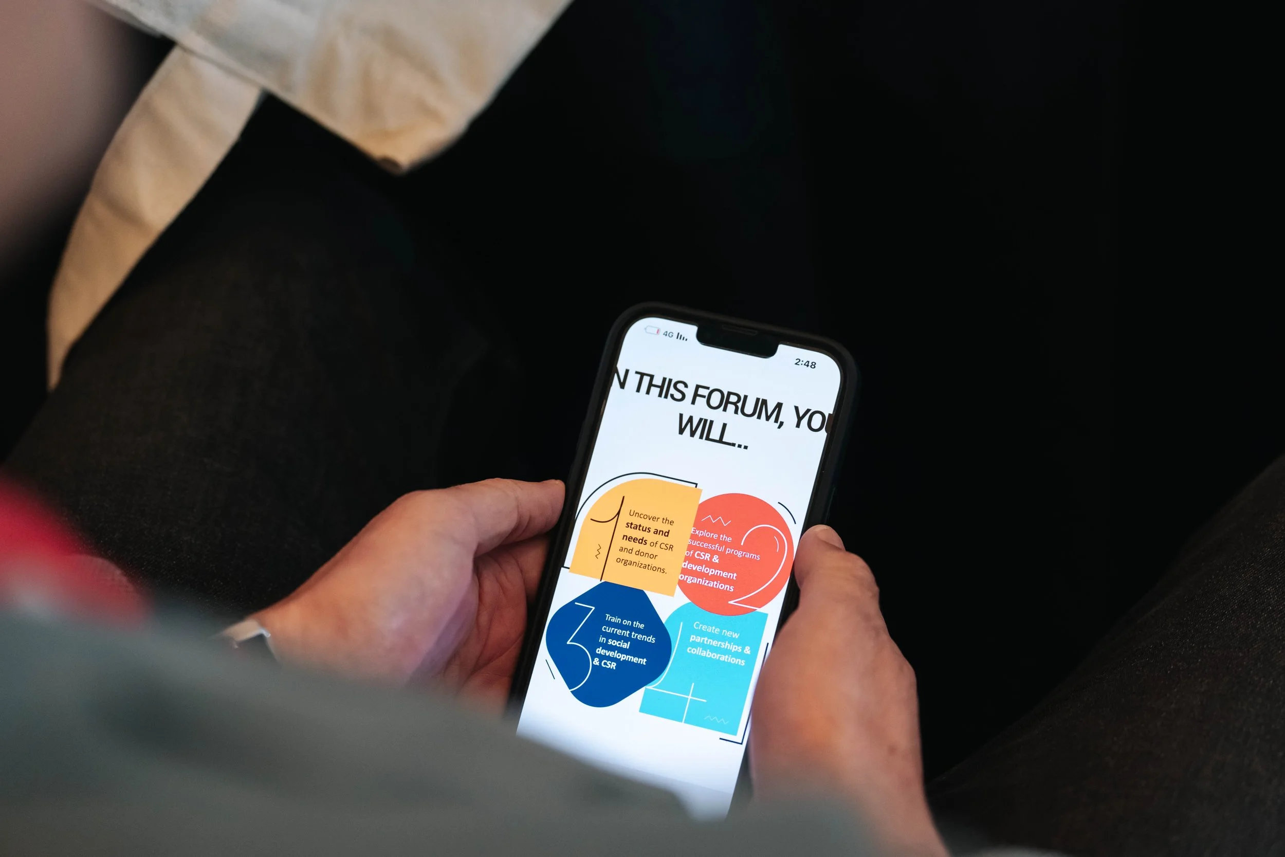 Person holding a phone displaying the colorful infographic of the Regional Sustainable Development Forum, First Edition, with steps for a program or workshop.