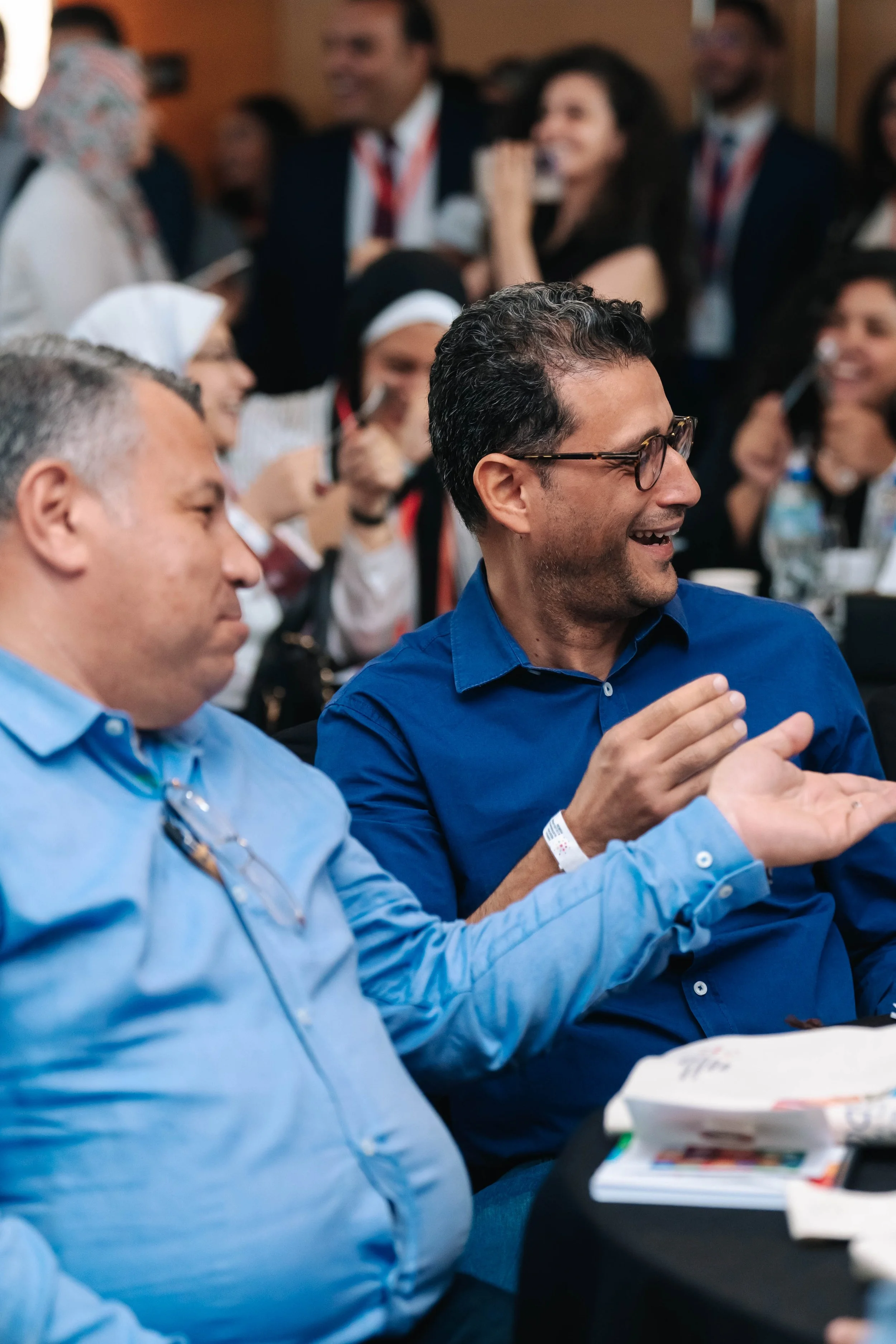 People attending Regional Sustainable Development Forum, First Edition, engaged and smiling, with laptops and notebooks on the table.