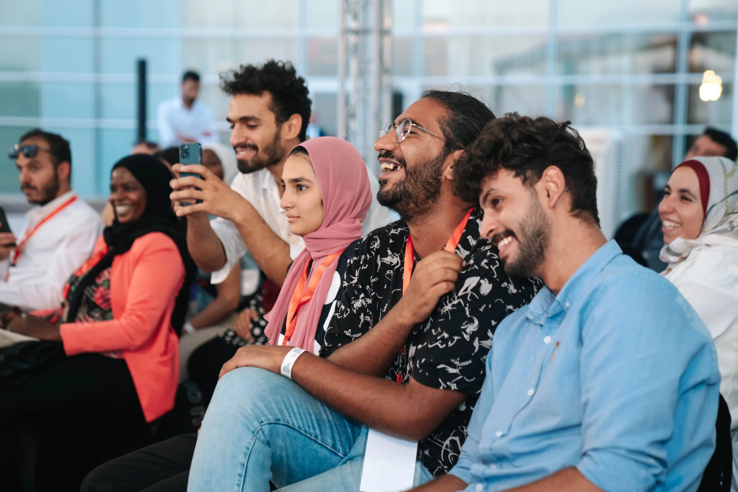 A Group of diverse people seated and smiling at the Regional Sustainable Development Forum, First Edition in a bright, modern venue.