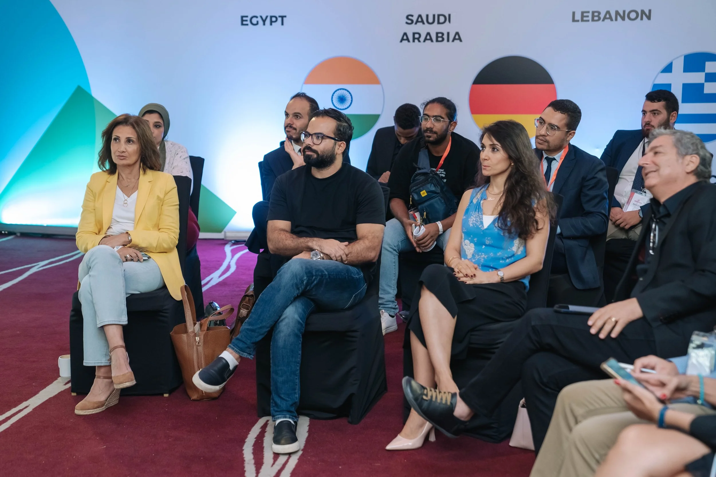 Group of people attending the Regional Sustainable Development Forum, First Edition, seated and listening to a speaker, with a backdrop displaying flags of Egypt, Saudi Arabia, and Lebanon.